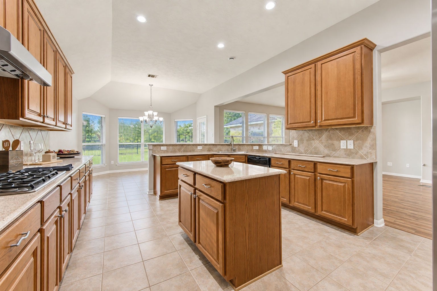 Bright and open kitchen featuring plenty of cabinet and counter space, a center island, gas cooktop, and an open layout that flows into the breakfast and living areas.