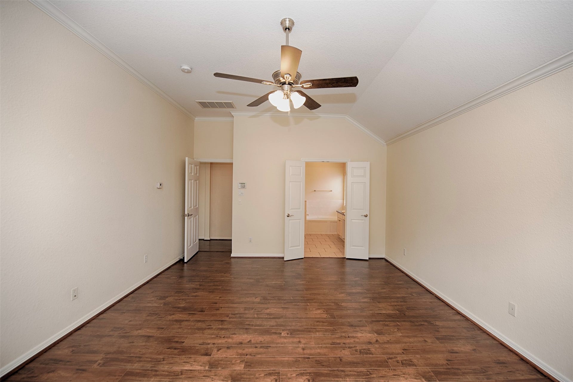 A view of the primary suite to the en suite bathroom. This room also features the gorgeous wood laminated floors.