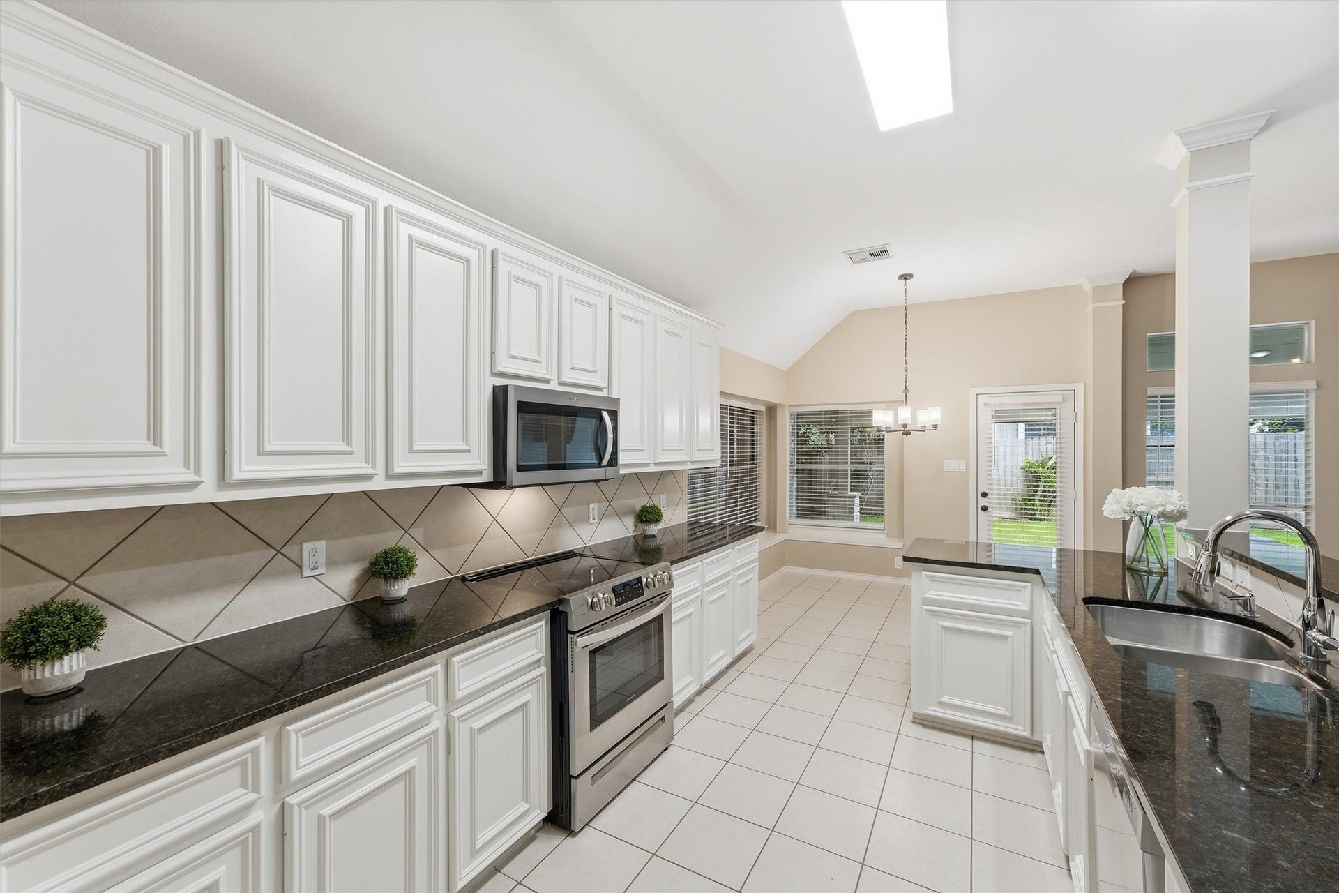 Functional kitchen layout featuring stainless steel appliances, extensive counter space, and decorative tile backsplash.