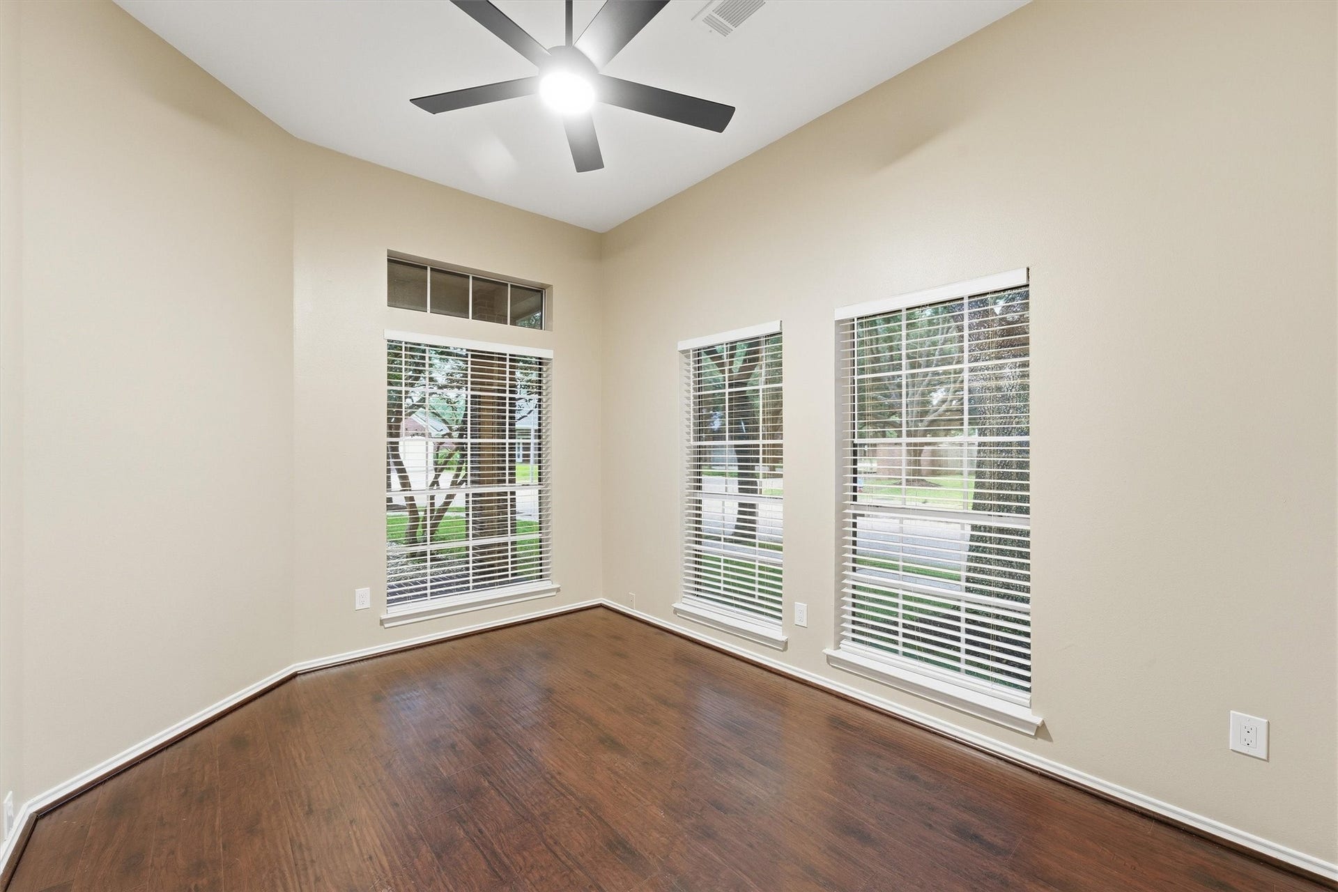 Bright home office or flex room featuring wood-style flooring, a modern ceiling fan, and large front-facing windows.