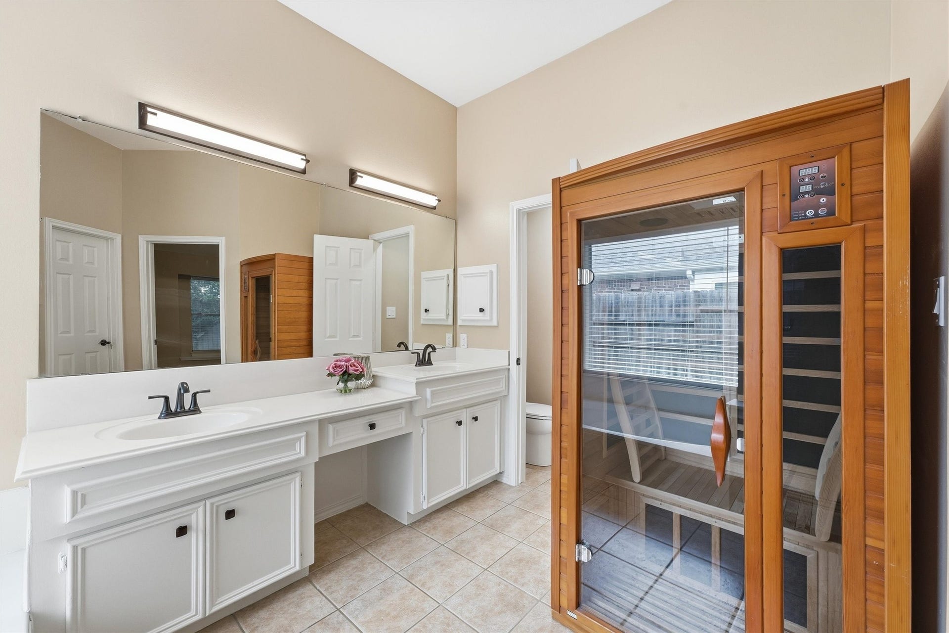 Spa-like primary bath features a long double vanity with a makeup station, and crisp white cabinetry.
