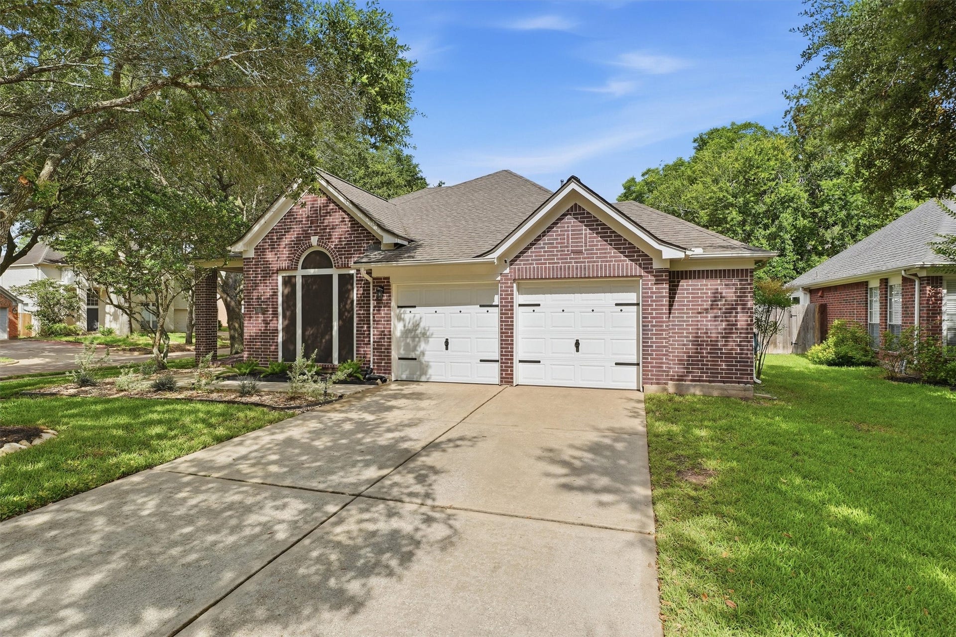 Angled view of the front exterior showing the wide driveway and landscaped front yard.