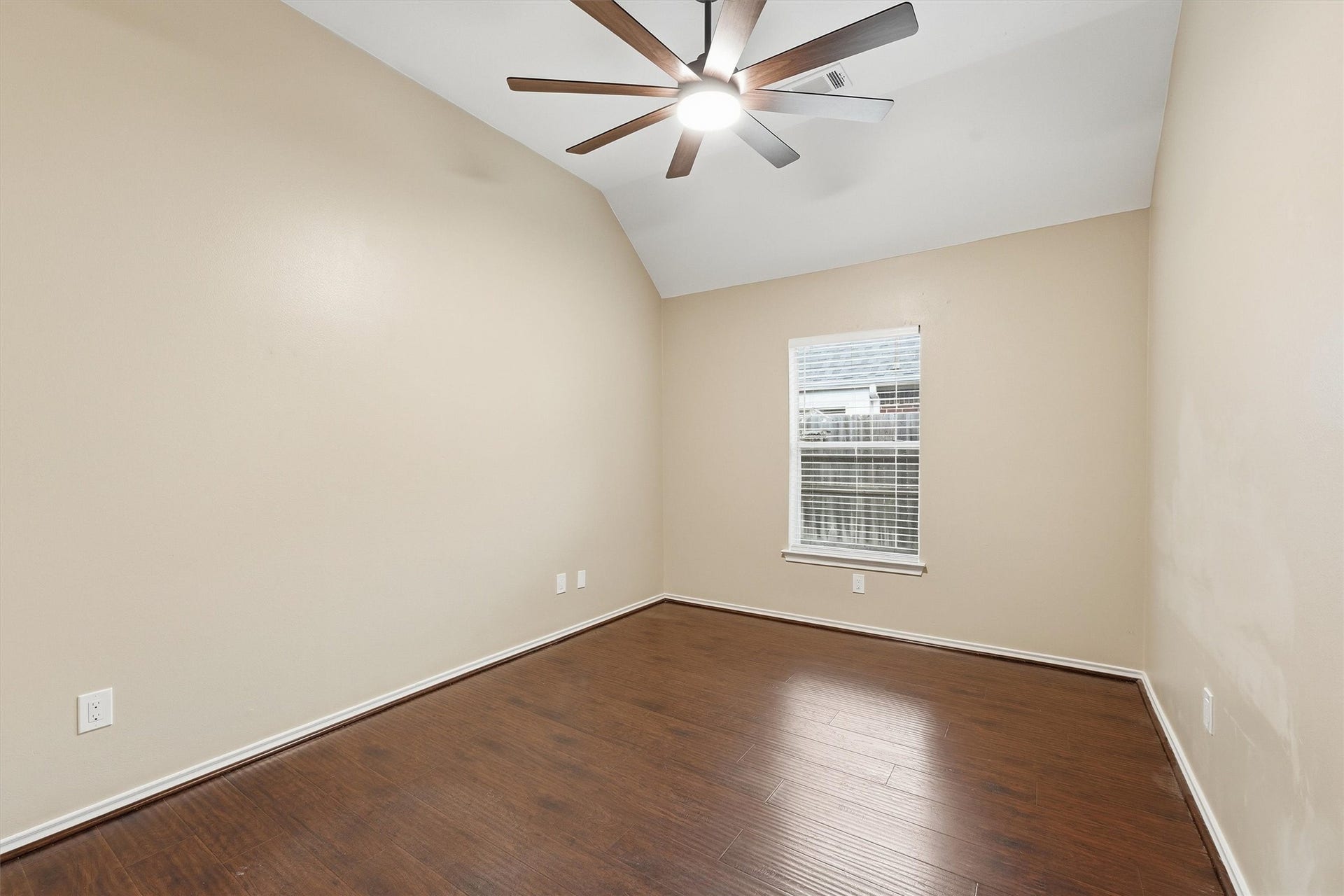 Versatile bedroom  highlighted by striking floor-to-ceiling arched windows, beautiful hardwood flooring, and a modern ceiling fan.