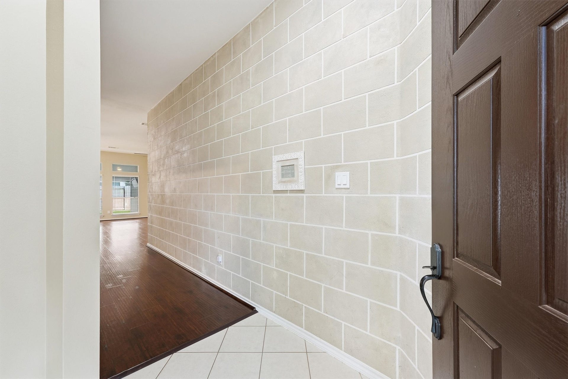 Foyer entry featuring a light tile floor, a faux-stone accent wall, and views into the main living spaces.