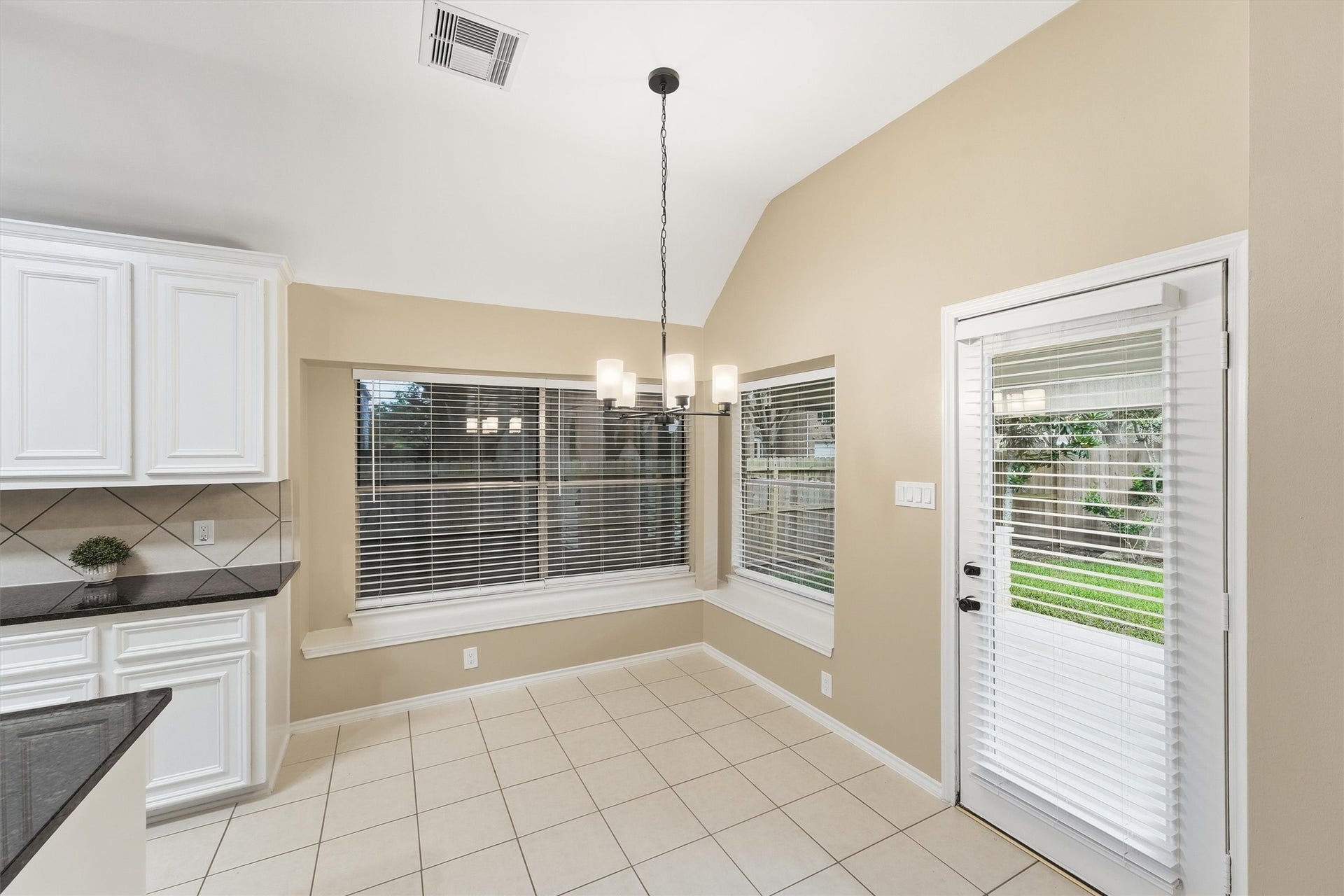Sunny breakfast room with a classic chandelier, built-in window seating, and direct access to the backyard.