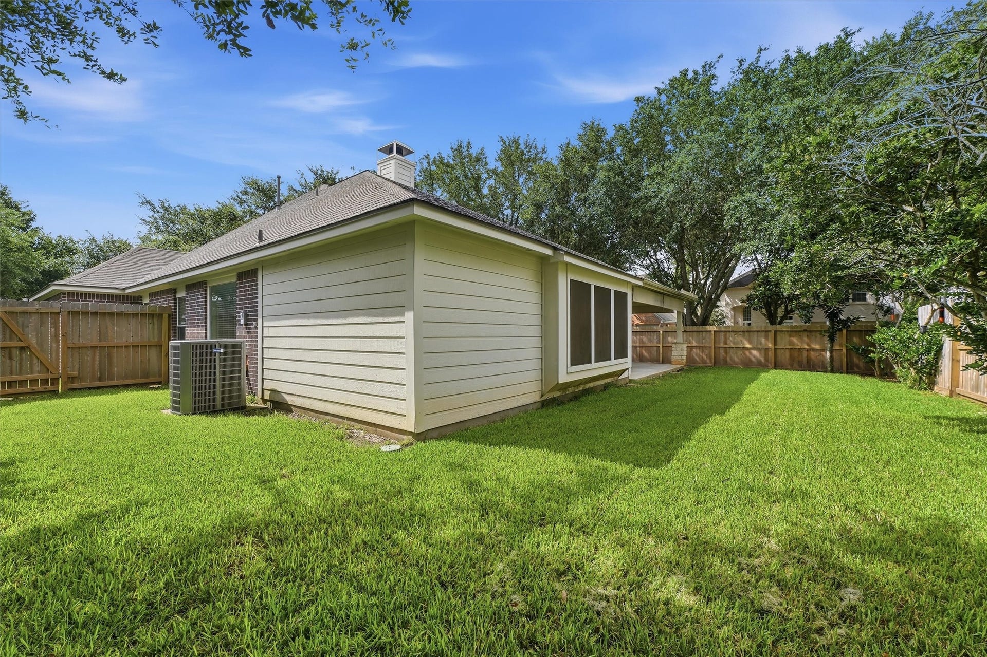 Spacious, fully fenced backyard featuring lush green grass, a clean exterior siding profile, and plenty of space for pets, play, or future gardening.