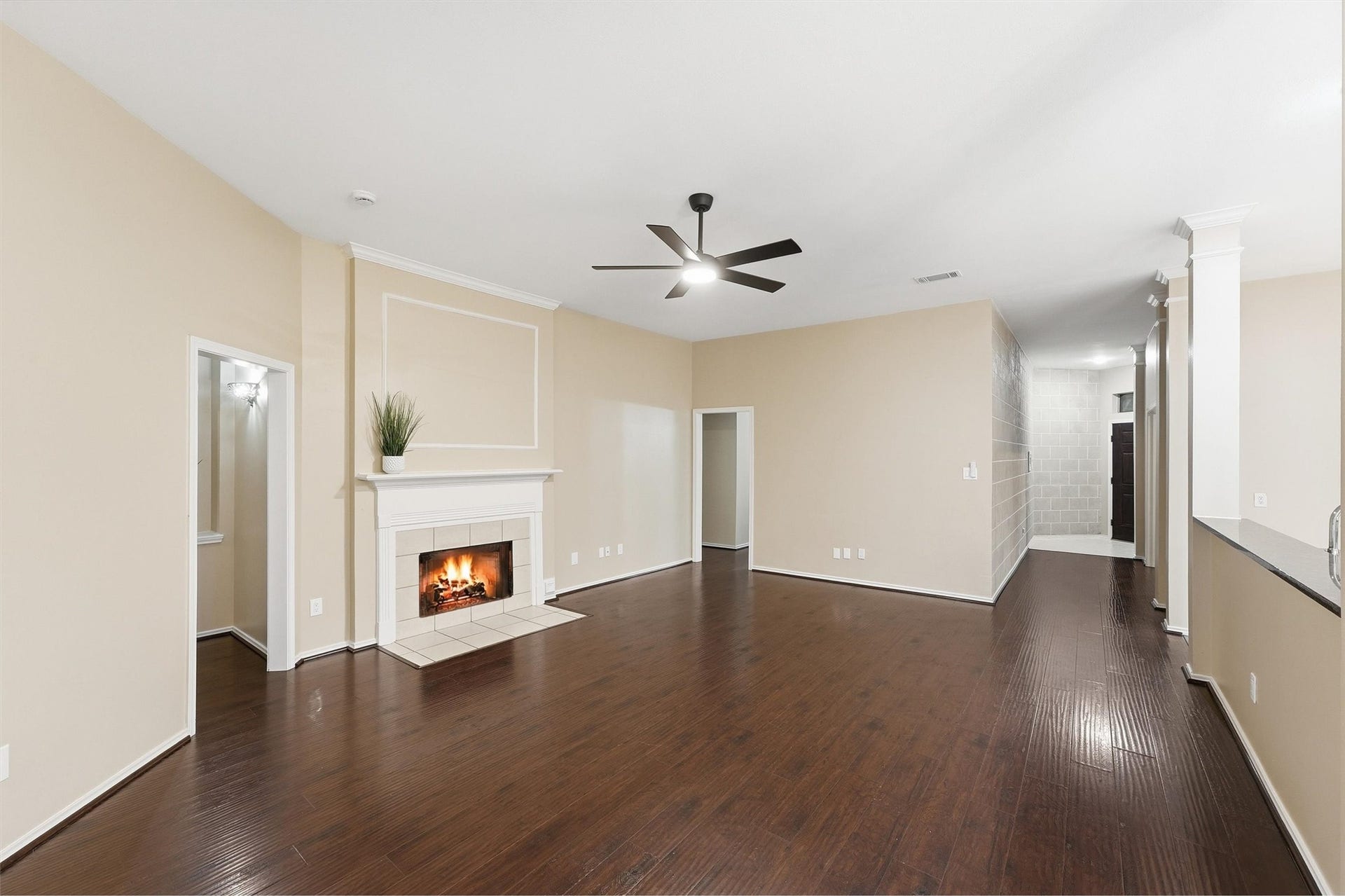 Spacious family room featuring a tile-surfaced fireplace, rich hardwood floors, high ceilings, and an updated contemporary ceiling fan. The open layout flows seamlessly into adjacent spaces.