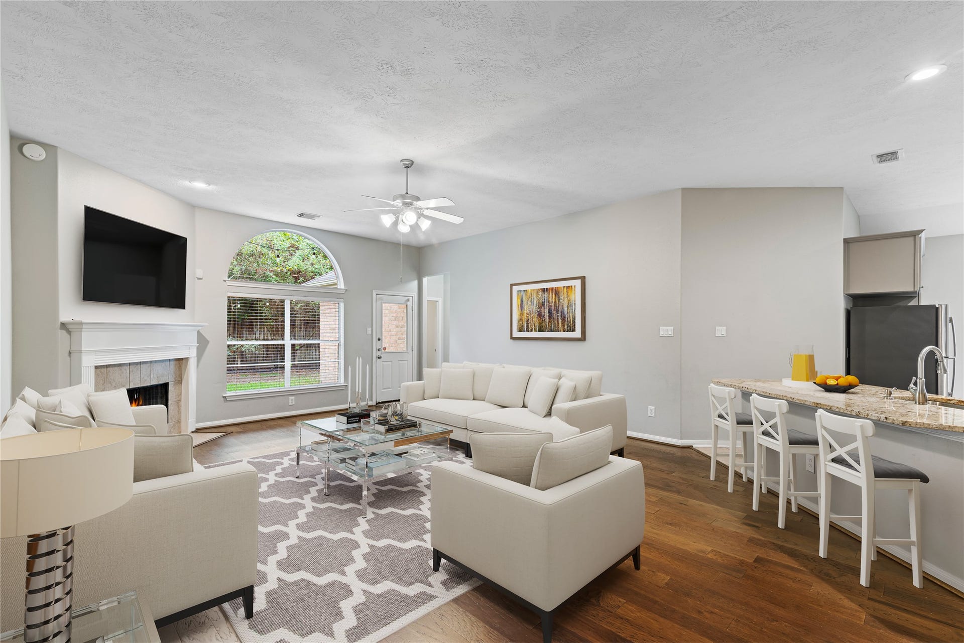 66 Bryce Branch Circle, Spring, TX 77382 Virtually Staged: Spacious open-concept family room featuring a cozy fireplace and abundant natural light from large windows, seamlessly connecting to a modern kitchen with a breakfast bar.