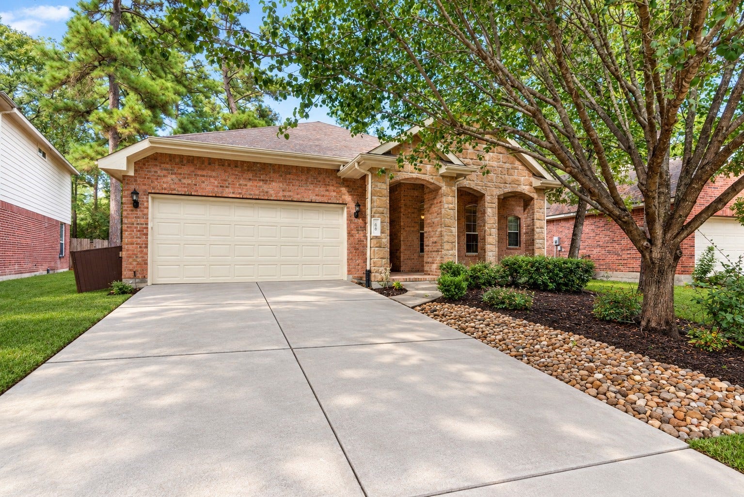 66 Bryce Branch Circle, Spring, TX 77382 Charming brick home with a two-car garage, nestled among mature trees, featuring a welcoming front porch and well-maintained landscaping.