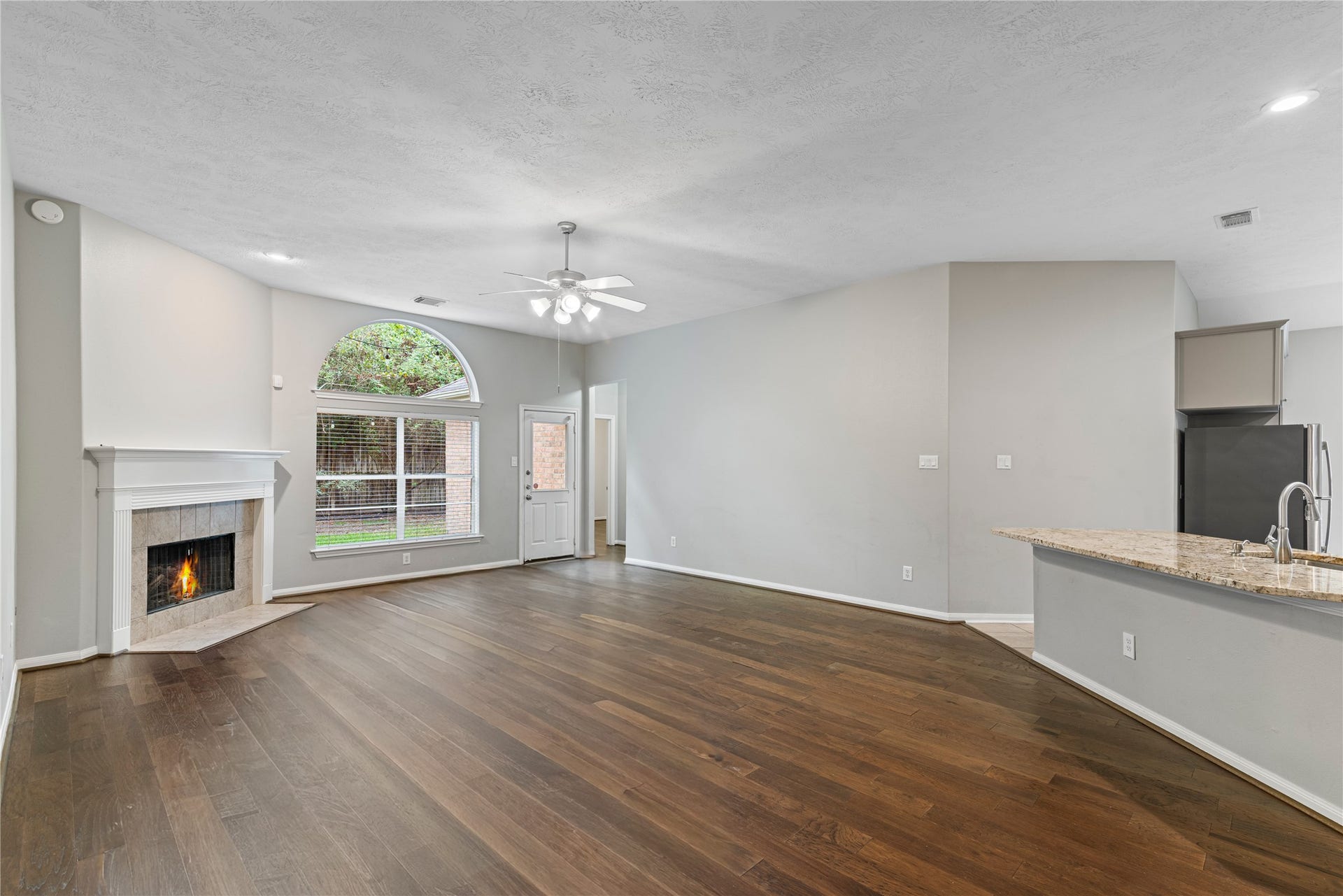 66 Bryce Branch Circle, Spring, TX 77382 Spacious living area with a cozy fireplace and abundant natural light from large windows. The open layout seamlessly connects to the modern kitchen, perfect for entertaining.