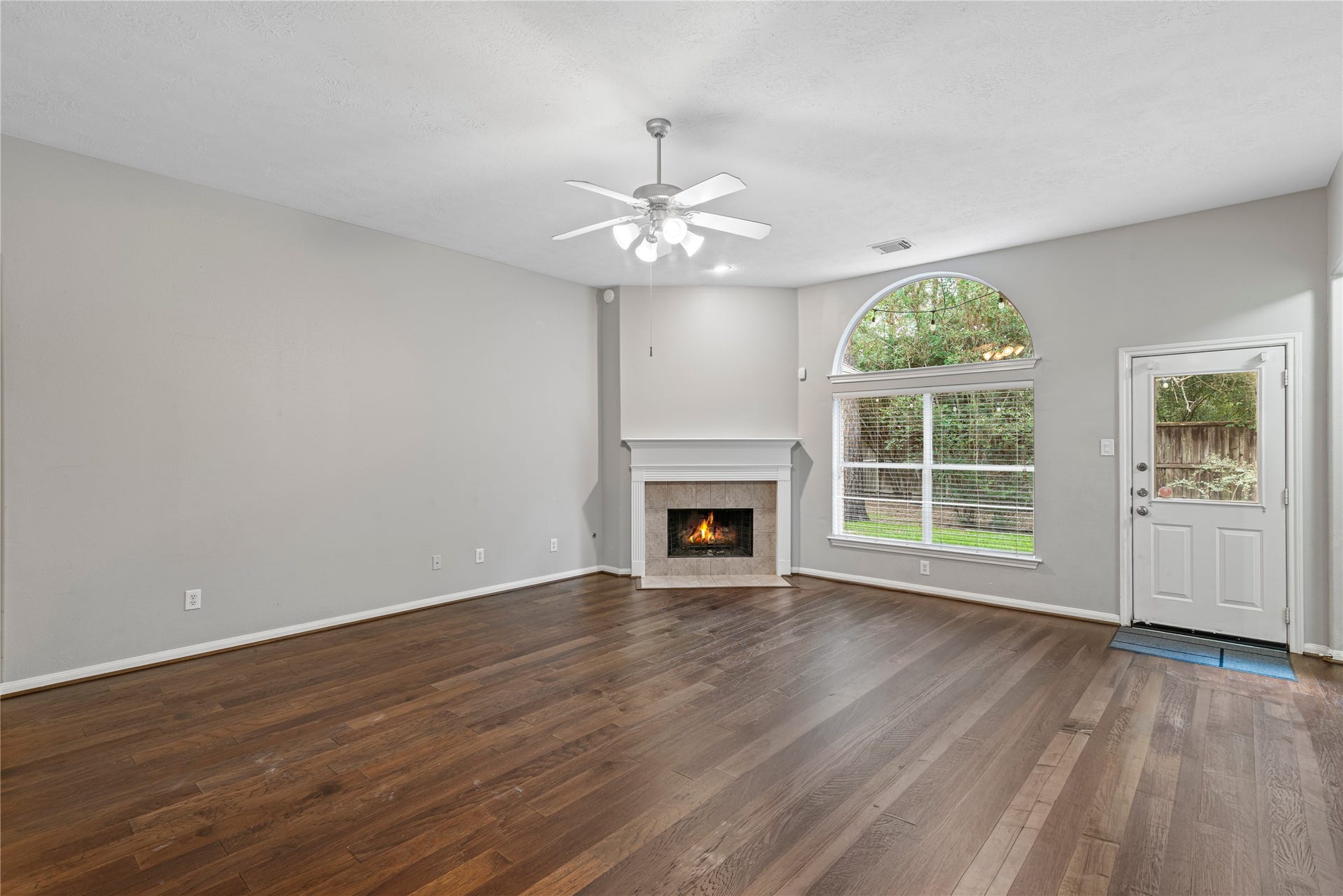 66 Bryce Branch Circle, Spring, TX 77382 Spacious family room with a cozy fireplace and abundant natural light from large arched windows, creating a warm and inviting atmosphere.