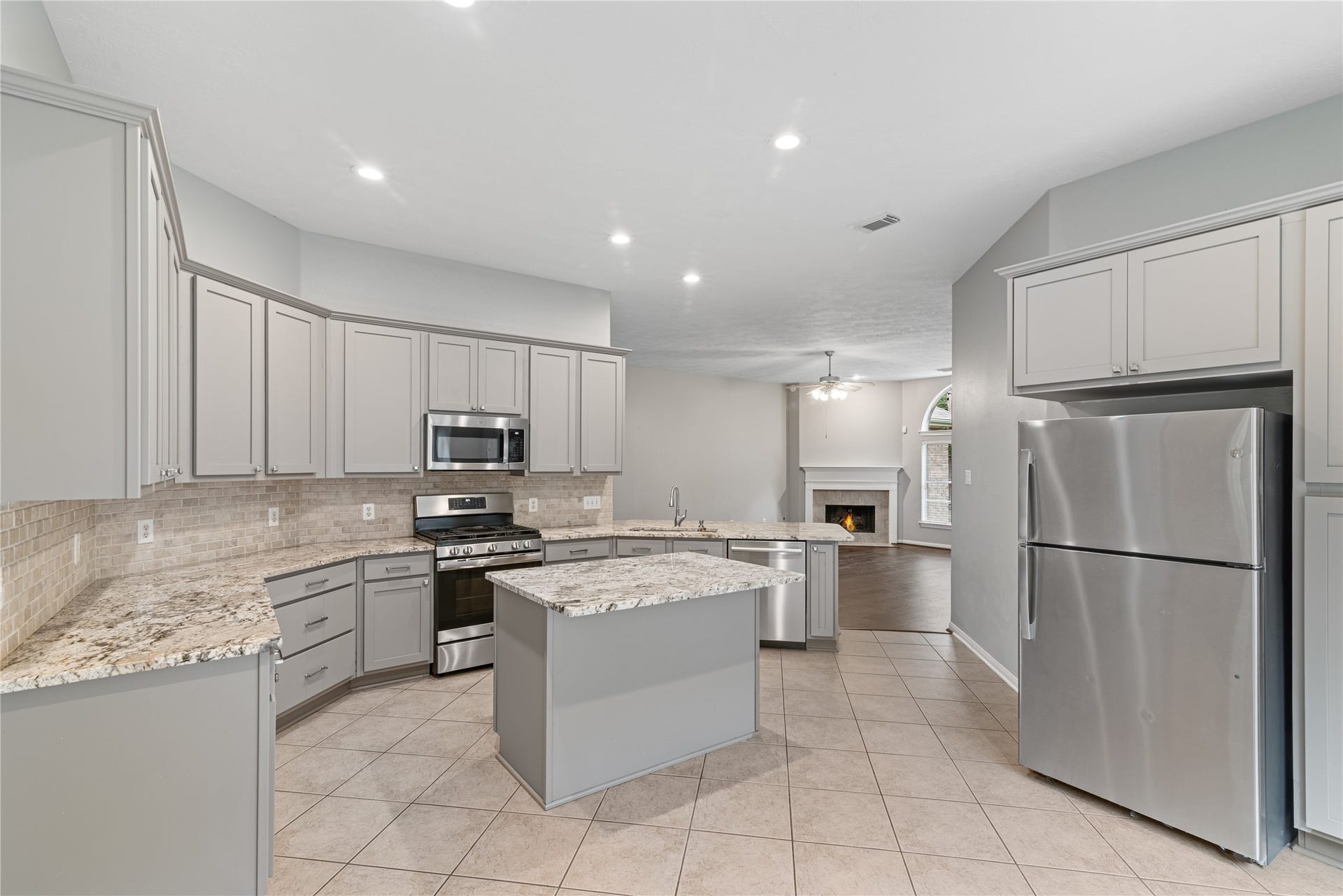 66 Bryce Branch Circle, Spring, TX 77382 Spacious kitchen with modern stainless steel appliances, updated granite countertops, backsplash and cabinetry, seamlessly flowing into a cozy family room.