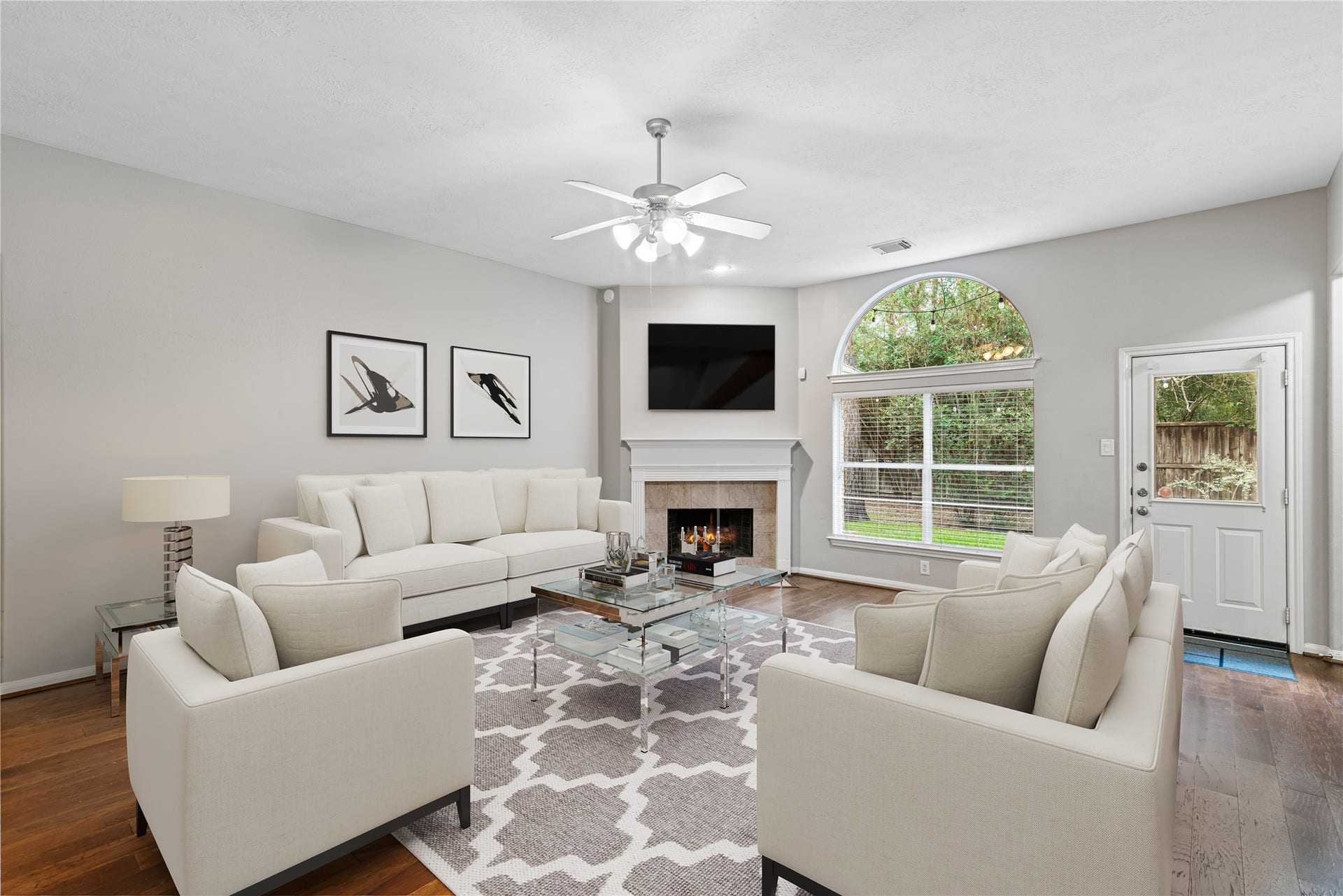 66 Bryce Branch Circle, Spring, TX 77382 Virtually Staged: Spacious and inviting family room featuring a cozy fireplace, large arched window, and elegant neutral decor, perfect for relaxation and entertaining.