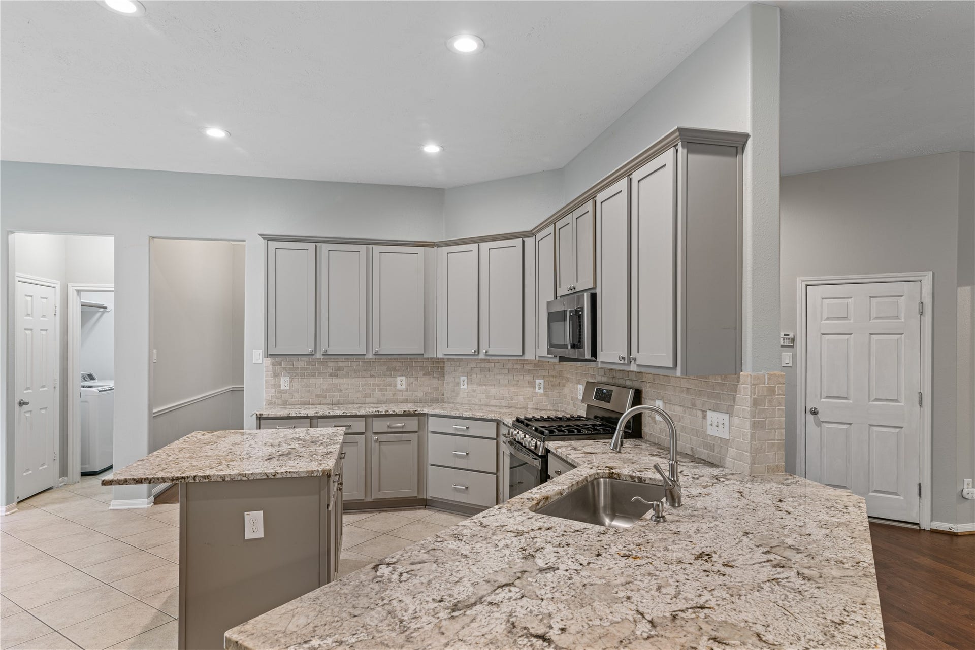66 Bryce Branch Circle, Spring, TX 77382 Spacious kitchen with sleek granite countertops, stainless steel appliances, and ample cabinetry, featuring a convenient island and modern tile backsplash.