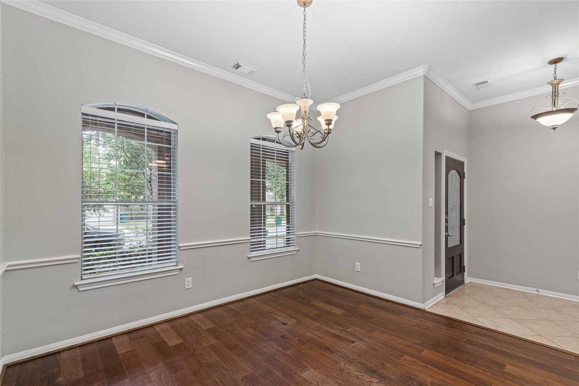 66 Bryce Branch Circle, Spring, TX 77382 Elegant dining area with laminate flooring, charming crown molding, and abundant natural light from arched windows, complemented by a classic chandelier.