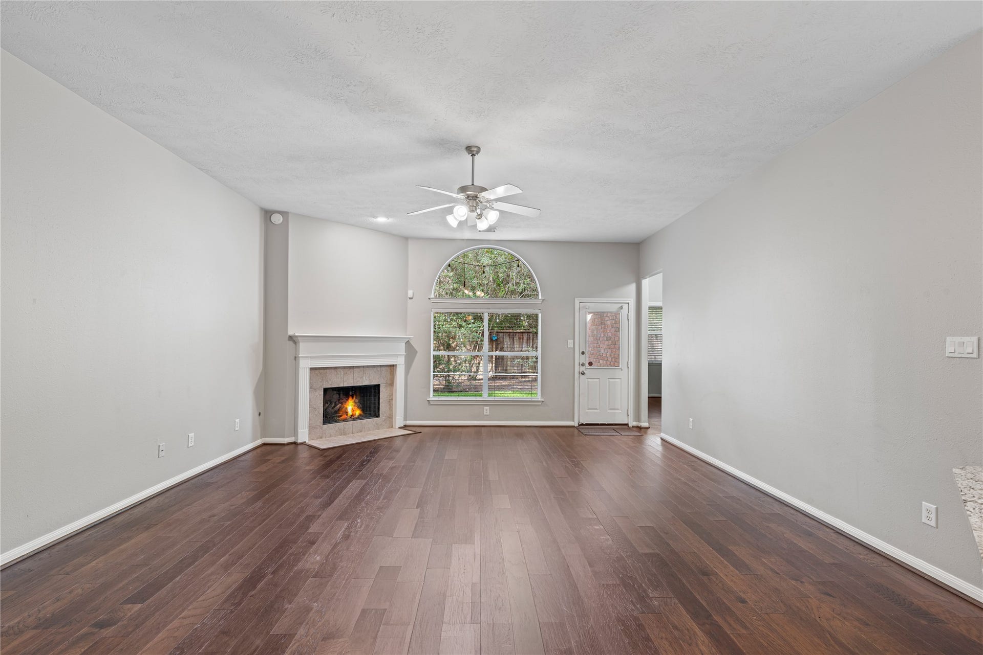 66 Bryce Branch Circle, Spring, TX 77382 Spacious living room featuring a cozy fireplace and abundant natural light from a large arched window.