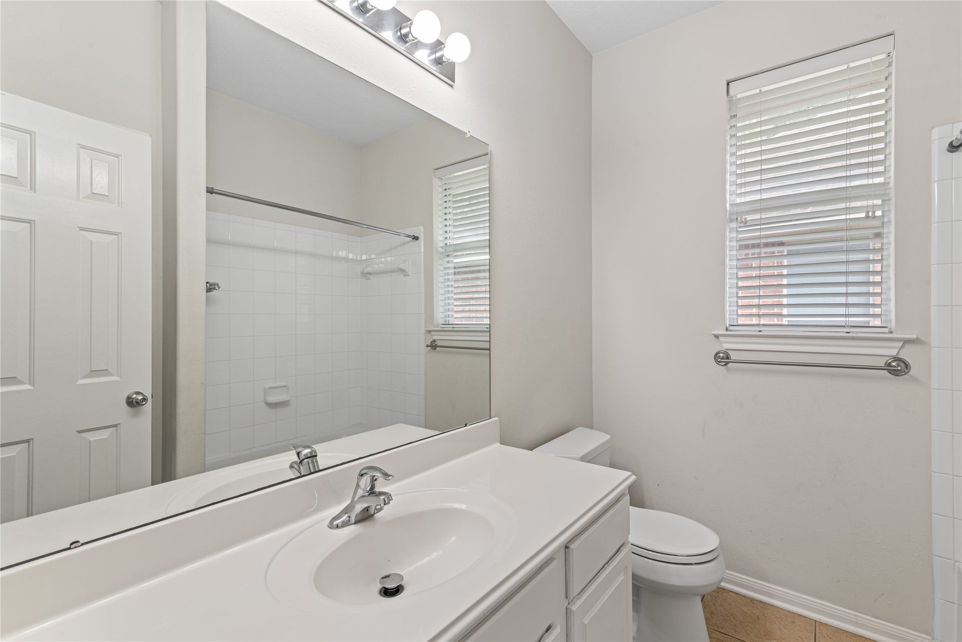 66 Bryce Branch Circle, Spring, TX 77382 Secondary bathroom featuring a large mirror, modern lighting, and a clean white vanity alongside a tiled shower and tub combination.