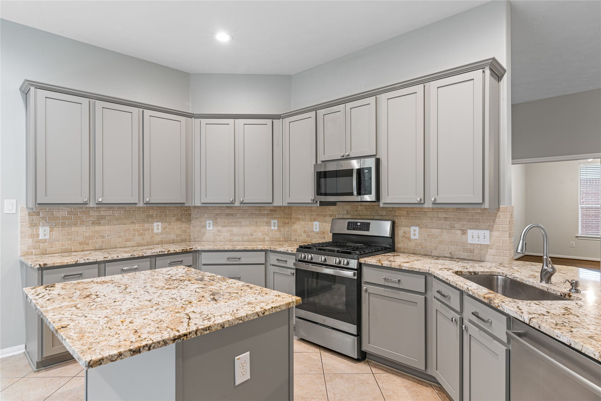66 Bryce Branch Circle, Spring, TX 77382 Spacious kitchen featuring elegant granite countertops, sleek stainless steel appliances, and ample grey cabinetry, perfect for culinary enthusiasts.
