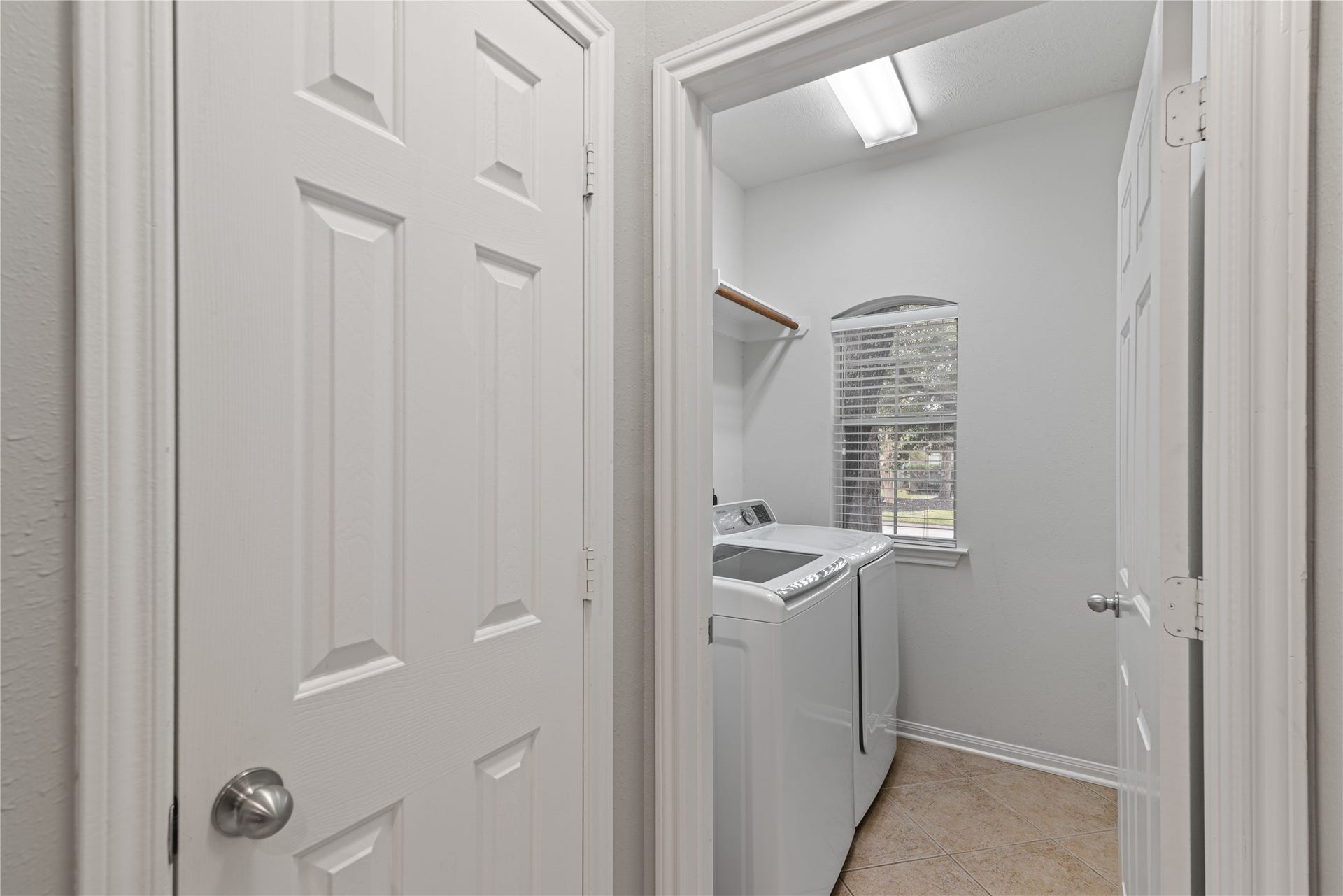 66 Bryce Branch Circle, Spring, TX 77382 Bright laundry room with modern appliances, tiled floor, and a cozy window for natural light.