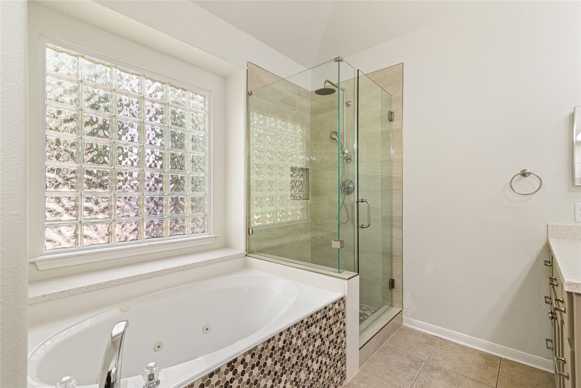 66 Bryce Branch Circle, Spring, TX 77382 Another view of the master bathroom featuring a luxurious soaking tub with mosaic tile accents, a spacious glass-enclosed shower, and abundant natural light through stylish glass block windows.