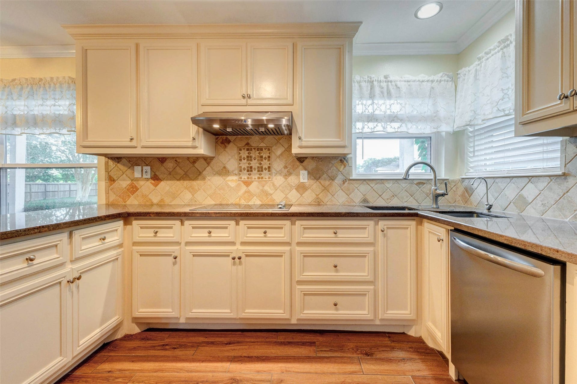 11418 Cedarwood Drive, Humble, TX 77338 The kitchen features classic cream cabinetry, a decorative tile backsplash, generous counter space, stainless dishwasher, under-cabinet lighting, and a window over the sink for natural light. With ample storage and a functional layout, this space is designed for everyday cooking, meal prep, and easy connection to nearby dining areas.