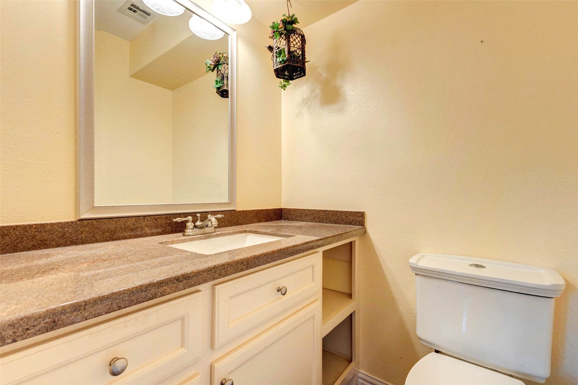 11418 Cedarwood Drive, Humble, TX 77338 The powder bath provides a convenient guest-friendly space with a long vanity, framed mirror, neutral finishes, and built-in open storage. Its location near the main living areas makes it practical for entertaining and everyday use, while the warm countertop and cabinetry create a simple, functional, and welcoming half bath.