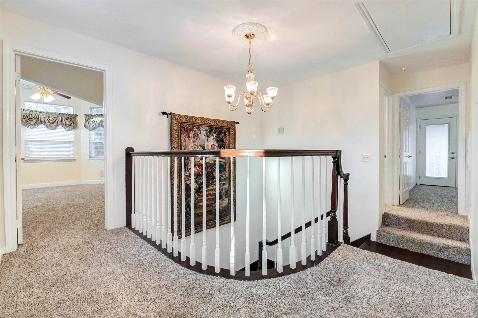 11418 Cedarwood Drive, Humble, TX 77338 The upstairs landing connects the bedrooms and living spaces with soft carpet, a decorative chandelier, and a classic railing overlooking the stairway below. This open transition area adds architectural interest while providing easy flow between the primary suite, secondary rooms, and additional upstairs living areas.