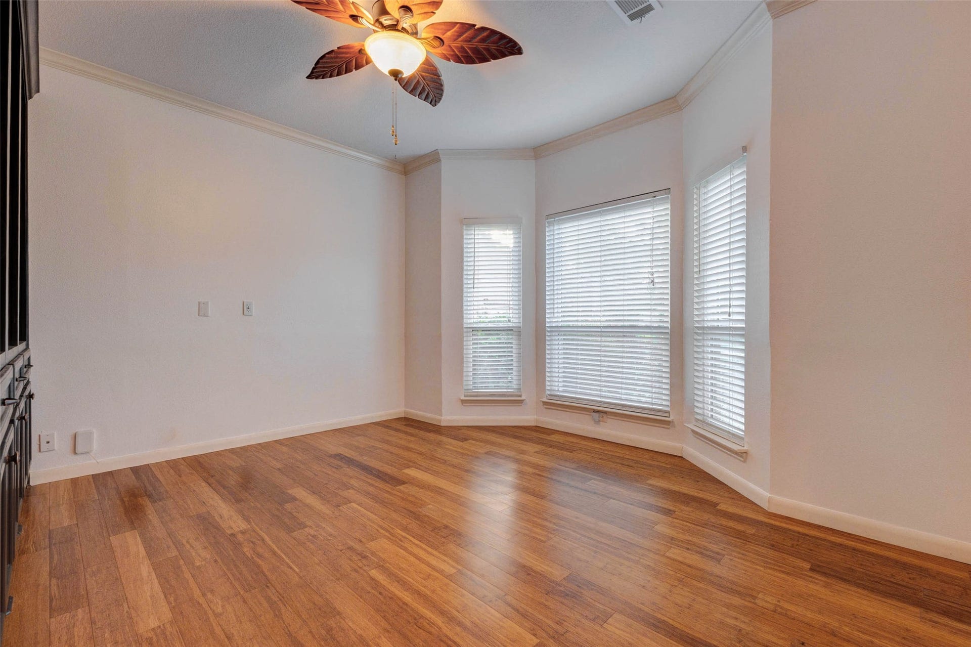 11418 Cedarwood Drive, Humble, TX 77338 A bright flexible room with warm wood-look flooring, crown molding, a ceiling fan, and a beautiful bay-style window arrangement offers endless possibilities. Use this inviting space as a home office, sitting room, playroom, music room, or quiet reading area. Natural light and classic trim details create a comfortable, polished feel.
