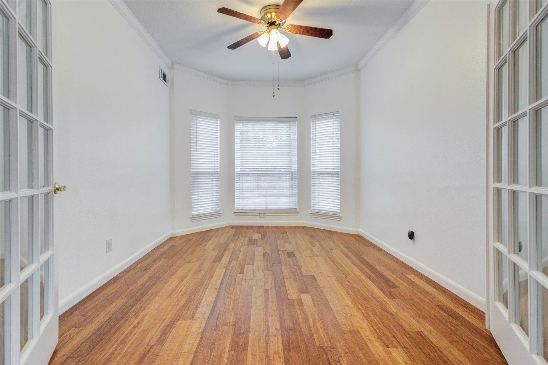 11418 Cedarwood Drive, Humble, TX 77338 French doors open into a light-filled room with wood-look flooring, crown molding, ceiling fan, and a wall of windows that bring in soft natural light. This flexible space works beautifully as a home office, formal sitting room, creative studio, nursery, or quiet retreat, offering privacy while still feeling connected to the home.