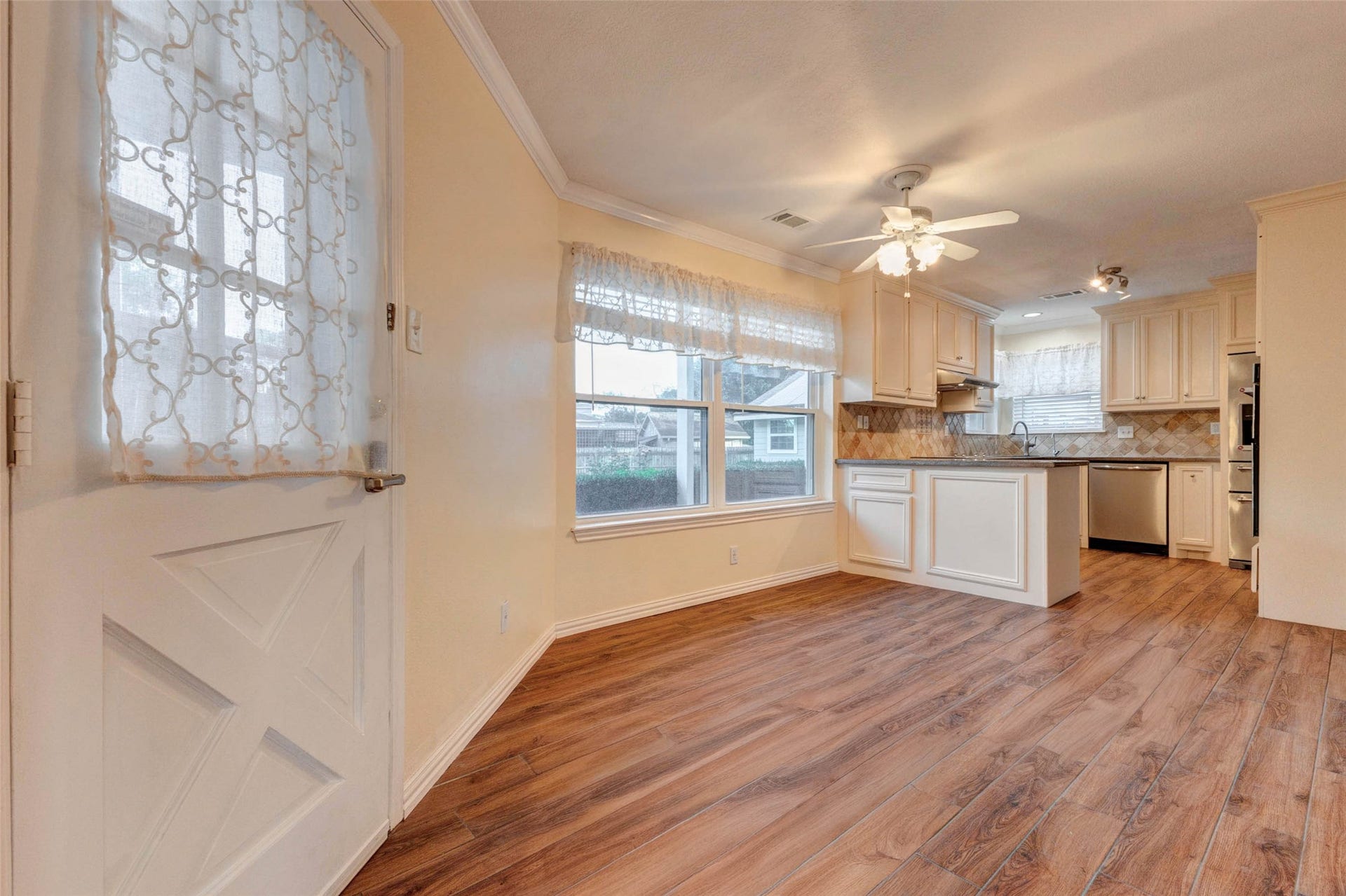 11418 Cedarwood Drive, Humble, TX 77338 The breakfast area offers a warm and welcoming everyday dining space with wood-look tile flooring, large windows, crown molding, and easy flow into the kitchen. A nearby exterior door adds convenient access to the outdoor living areas, making this a practical and inviting spot for morning coffee, casual meals, and daily routines.