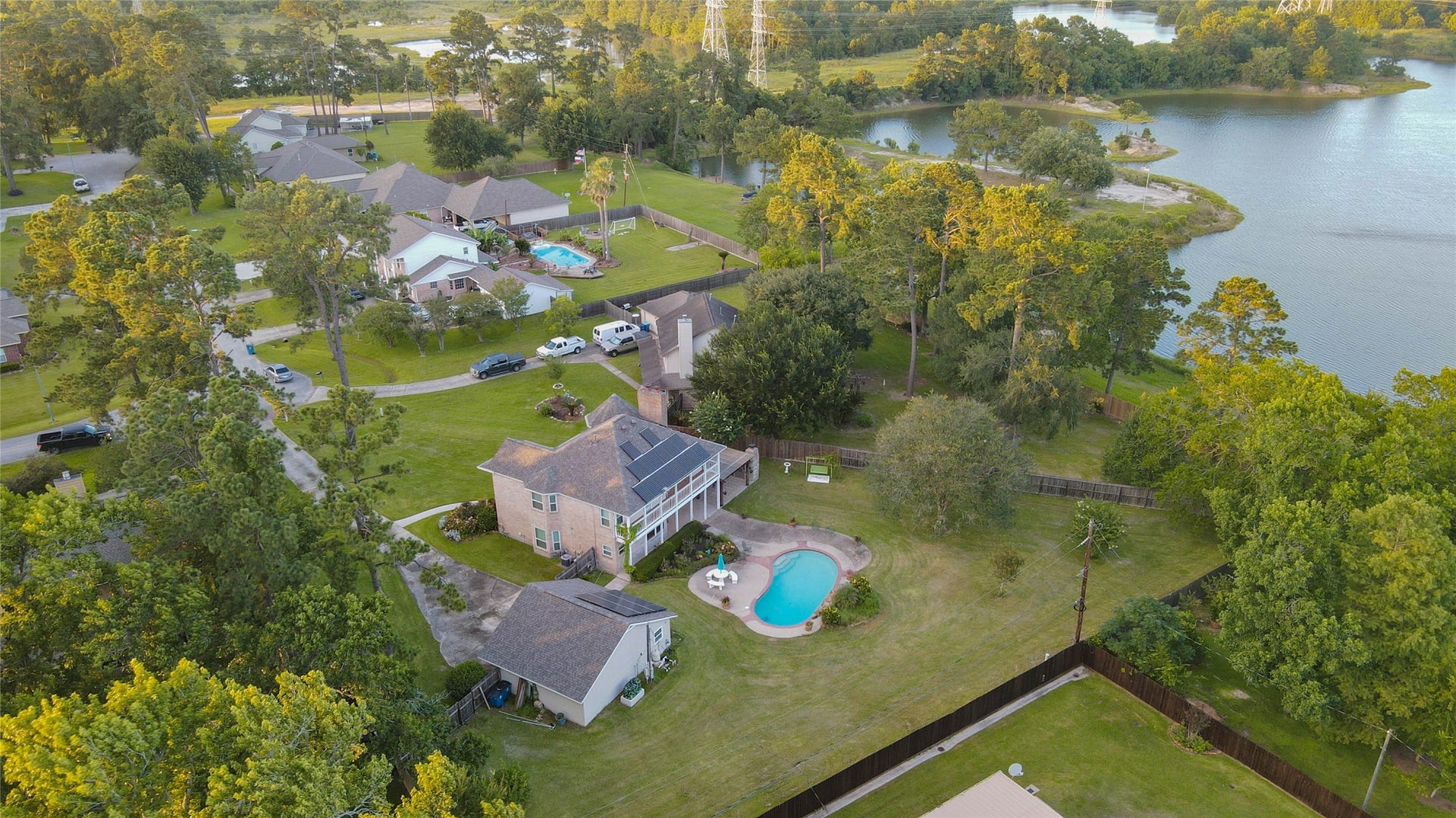 11418 Cedarwood Drive, Humble, TX 77338 Aerial photography reveals the full backyard experience, including the private pool, expansive lawn, detached garage, mature trees, fencing, and generous lot size. The home sits within a peaceful established neighborhood near scenic water views, offering a rare combination of outdoor living, privacy, space, and convenience in the Ramblewood community.