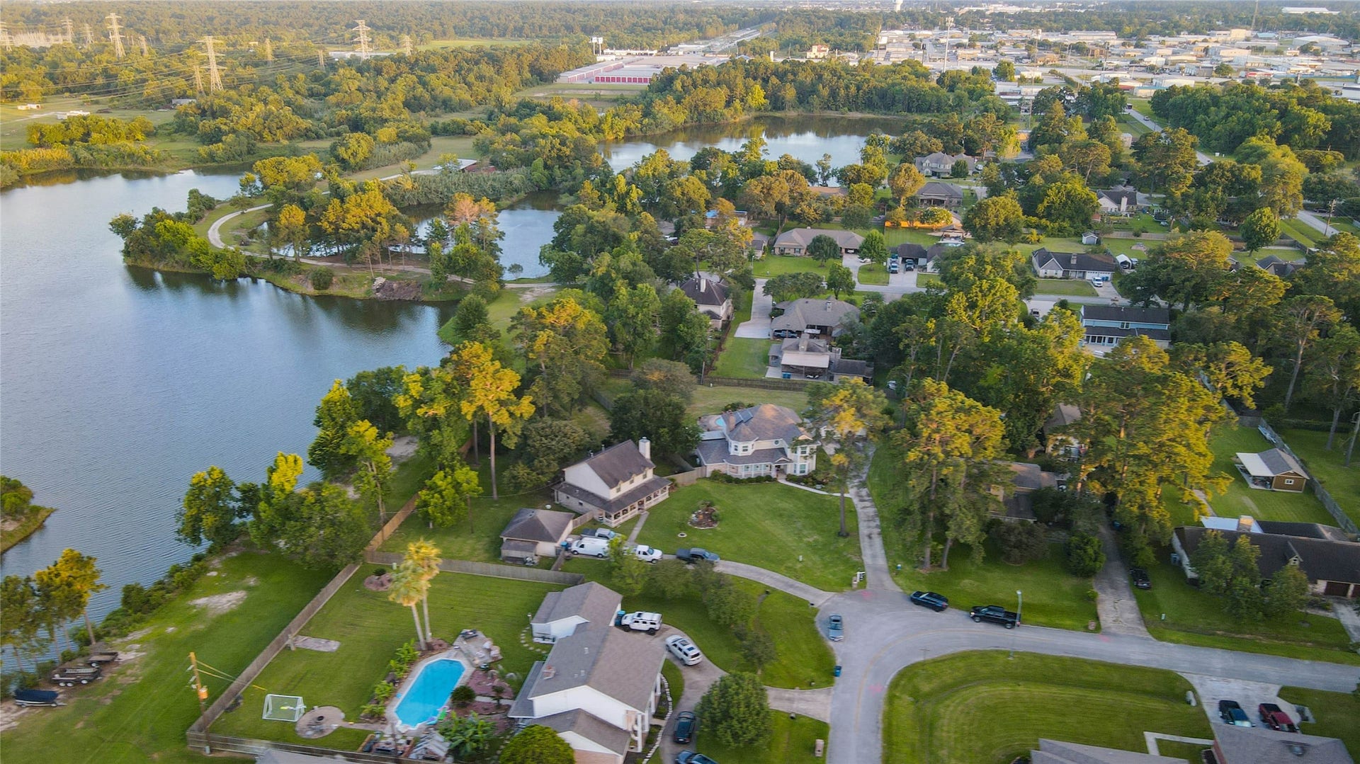 11418 Cedarwood Drive, Humble, TX 77338 This sweeping aerial perspective captures the homes exceptional location near beautiful lakes, green space, mature tree canopies, and established neighborhood streets. The property sits prominently on a generous lot with a long driveway, detached garage, pool, and open lawn, offering buyers a clear view of the privacy, scale, and lifestyle setting.