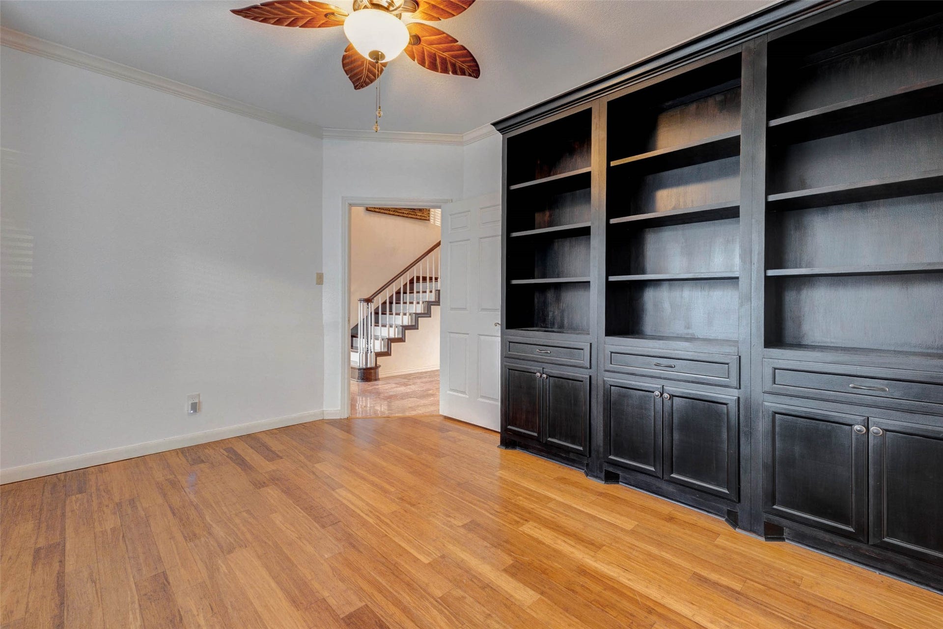 11418 Cedarwood Drive, Humble, TX 77338 This dedicated study features rich built-in shelving and cabinetry, warm wood-look flooring, crown molding, and a ceiling fan. The custom built-ins provide excellent space for books, dcor, files, and display pieces, making this room ideal for a home office, library, homework zone, or private retreat just off the main living areas.