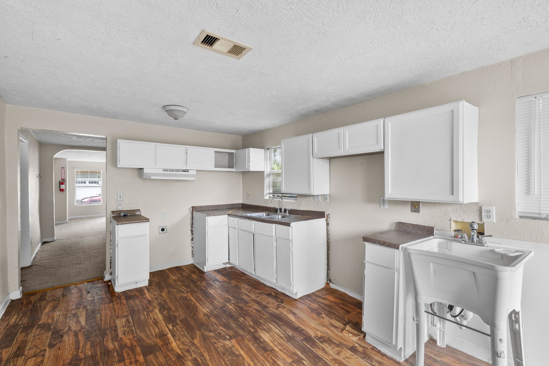 3502 Europa Street, Houston, TX 77022 Spacious kitchen with white cabinetry, ample counter space, double-basin sink, and wood-look flooring.