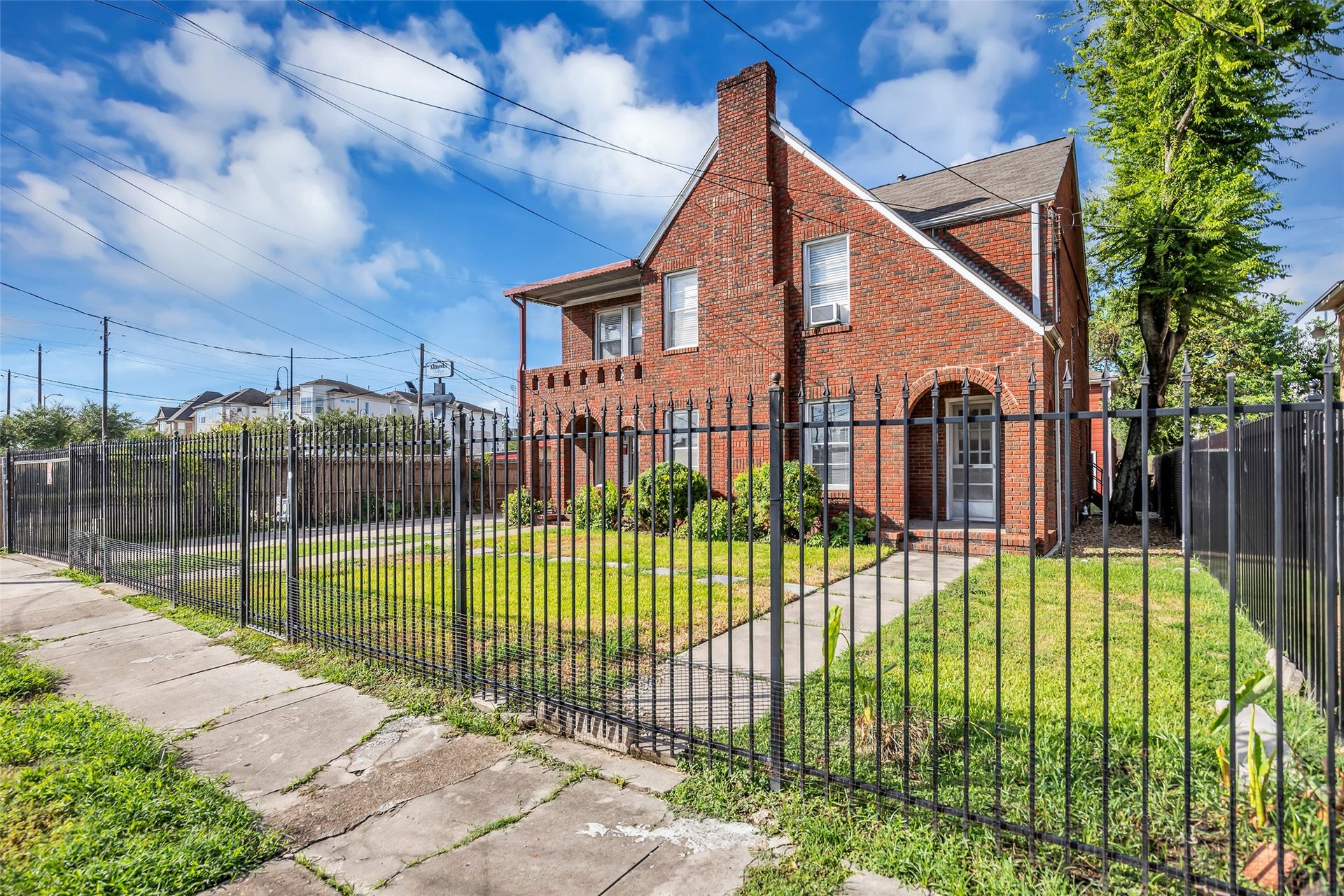 The front of the two-story brick duplex features iron fencing around the property, adding definition and a classic touch to the exterior while providing a clear boundary for the home.