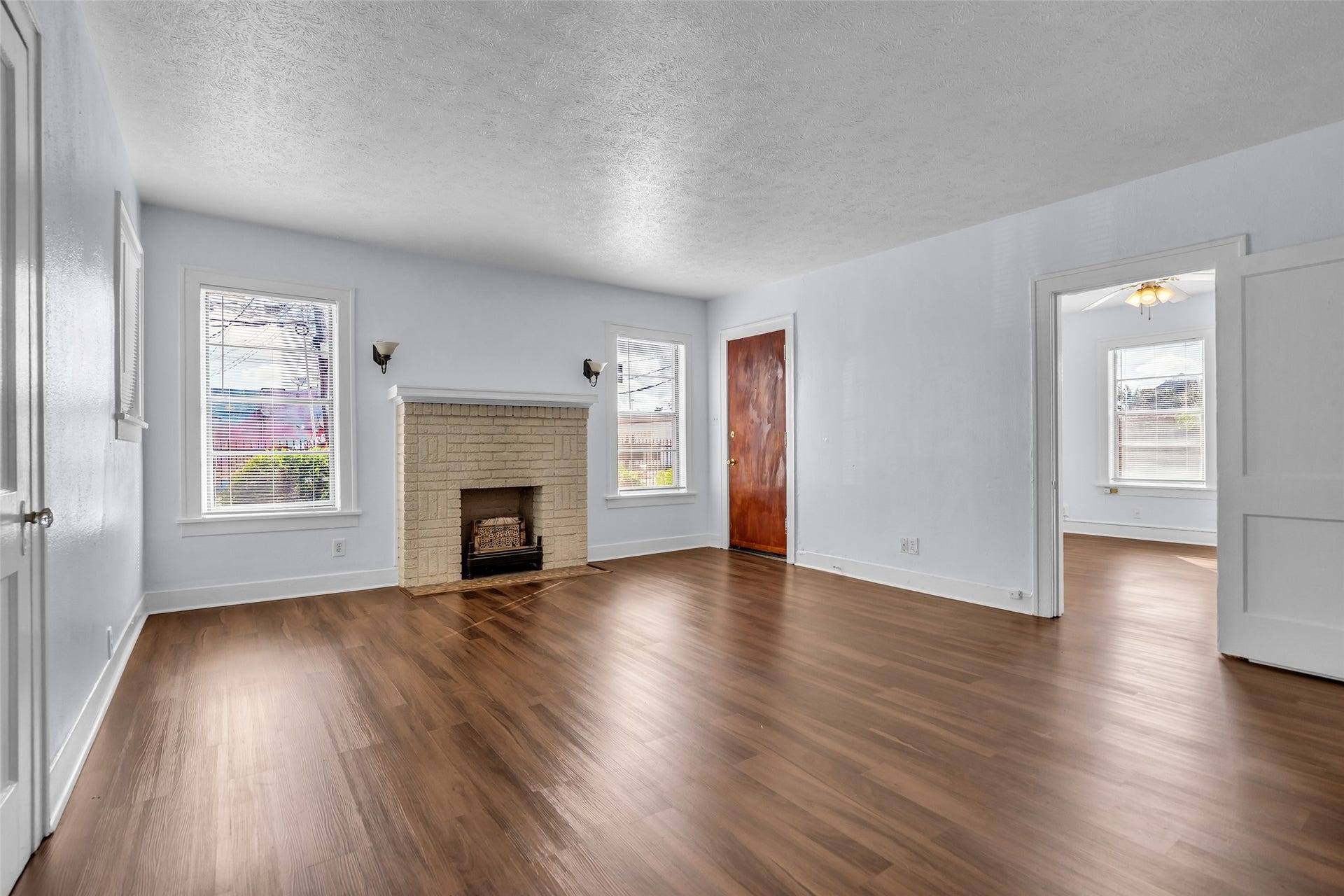Spacious living room in the two-story brick duplex featuring a classic fireplace and warm wood flooring.