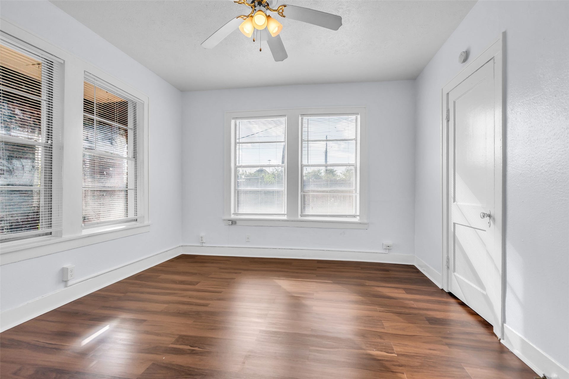 The primary bedroom is filled with natural light from windows along three walls, creating a bright and inviting space with plenty of room for comfortable furnishings.
