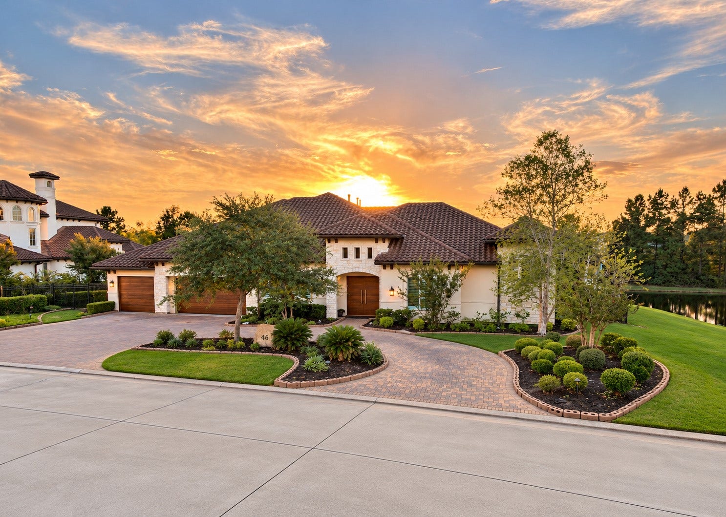 46 Lamerie Way, The Woodlands, TX 77382 Stunning sunset views create a breathtaking backdrop for this luxury estate, showcasing its elegant architecture, circular driveway, and beautifully landscaped grounds.