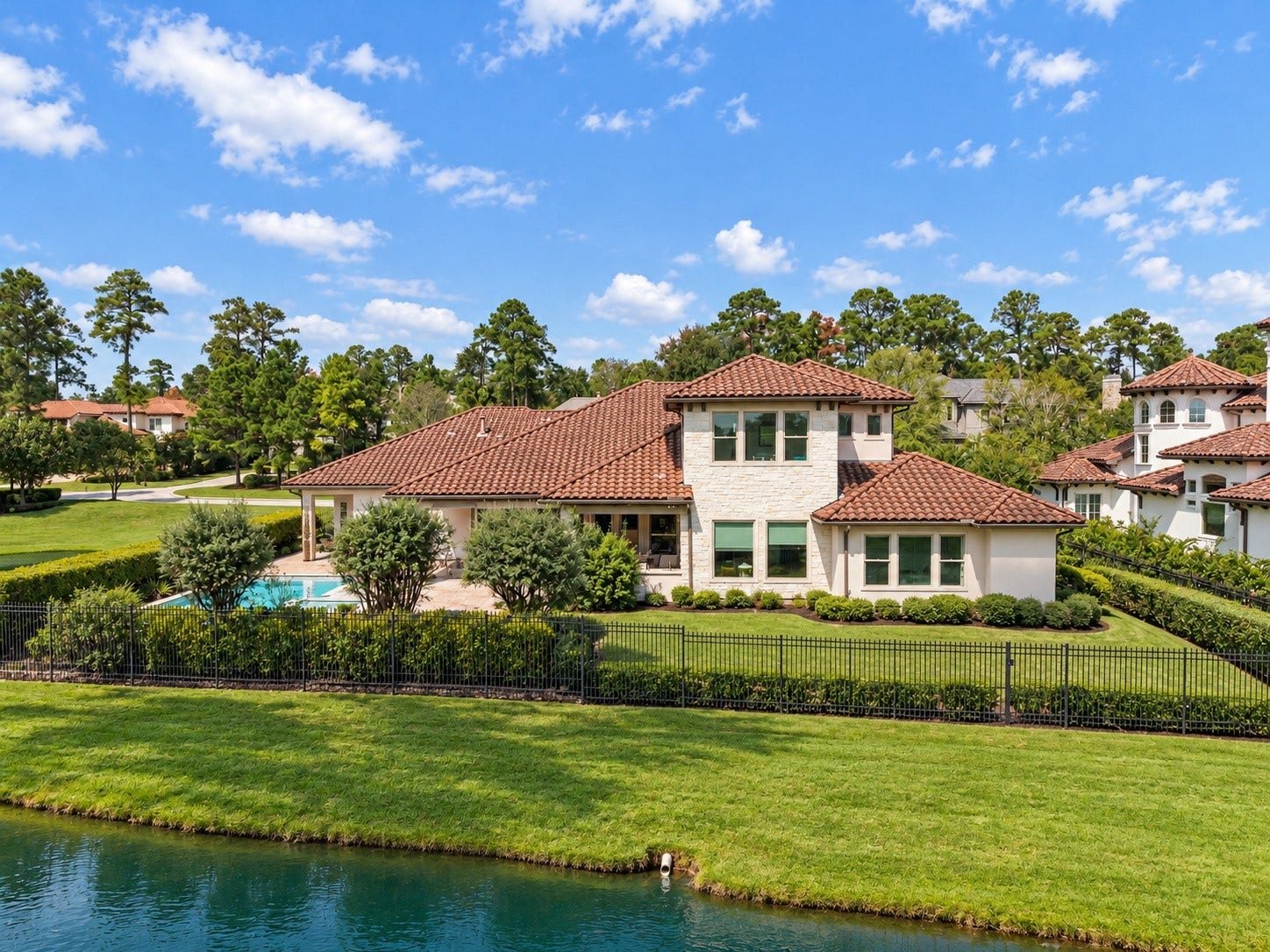 46 Lamerie Way, The Woodlands, TX 77382 Beautiful rear elevation overlooking the water, featuring lush green lawns, mature landscaping, and an exceptional waterfront setting.