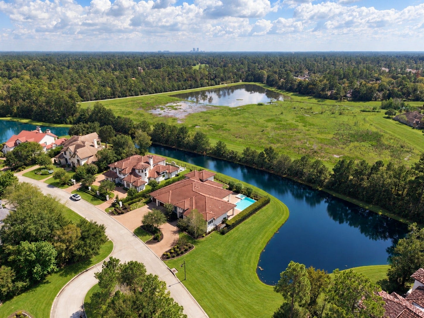 46 Lamerie Way, The Woodlands, TX 77382 Spectacular aerial view showcasing the estate's unique peninsula setting, with sparkling water on both sides and breathtaking views in every direction