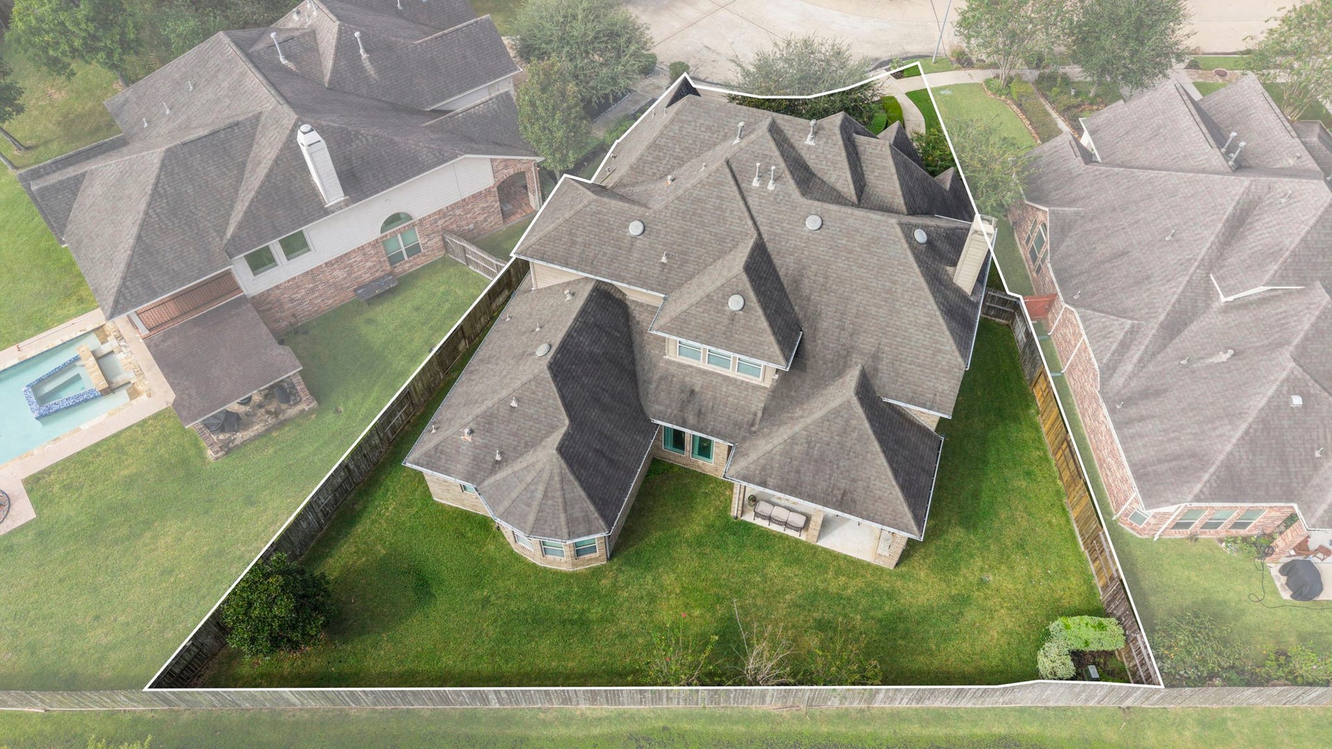 34 Stefano Way, Missouri City, TX 77459 Elevated rear aerial angle featuring a highlighted boundary line around the backyard, showcasing the full lot footprint, rear elevation brickwork, bay window section, and large covered patio.