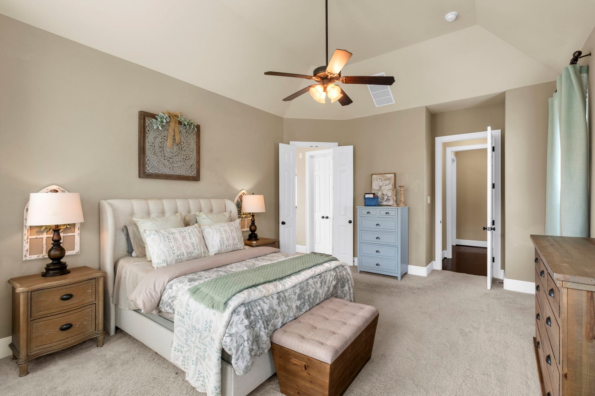 34 Stefano Way, Missouri City, TX 77459 Alternate view of the primary bedroom showing the expansive floor plan, tray ceiling design, neutral wall color, and double doors leading into the ensuite primary bathroom.