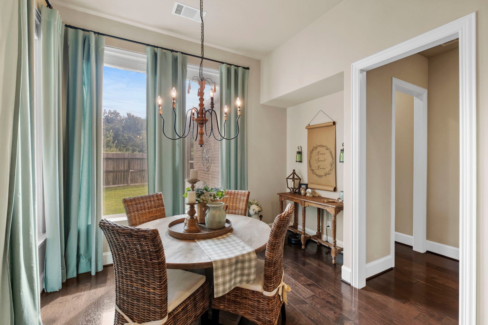 34 Stefano Way, Missouri City, TX 77459 Light-filled breakfast room featuring large picture windows with yard views, a decorative chandelier lighting mount, warm hardwood floors, and direct access through a wide trim case opening to the surrounding common areas.
