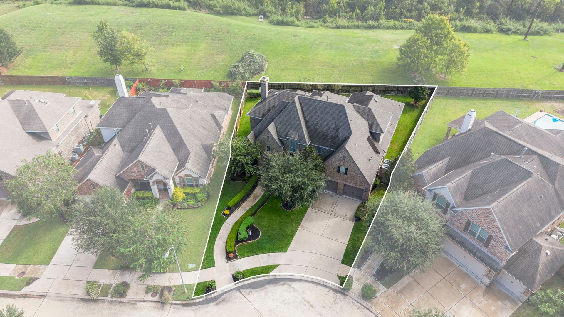 34 Stefano Way, Missouri City, TX 77459 Elevated front-facing aerial photo outlining the property boundaries, deep concrete multi-car driveway, curated front yard landscaping, mature shade trees, and stone exterior finish.