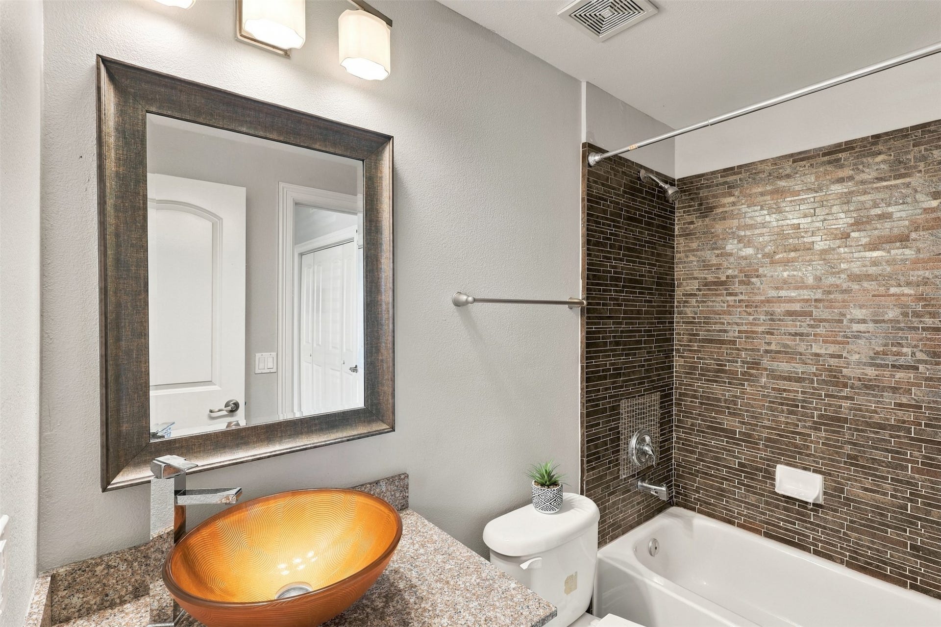 3501 Chenevert Street, #3, Houston, TX 77004 Stylish bathroom featuring a sleek vessel sink, elegant granite countertops, and a modern tile backsplash in the shower area.