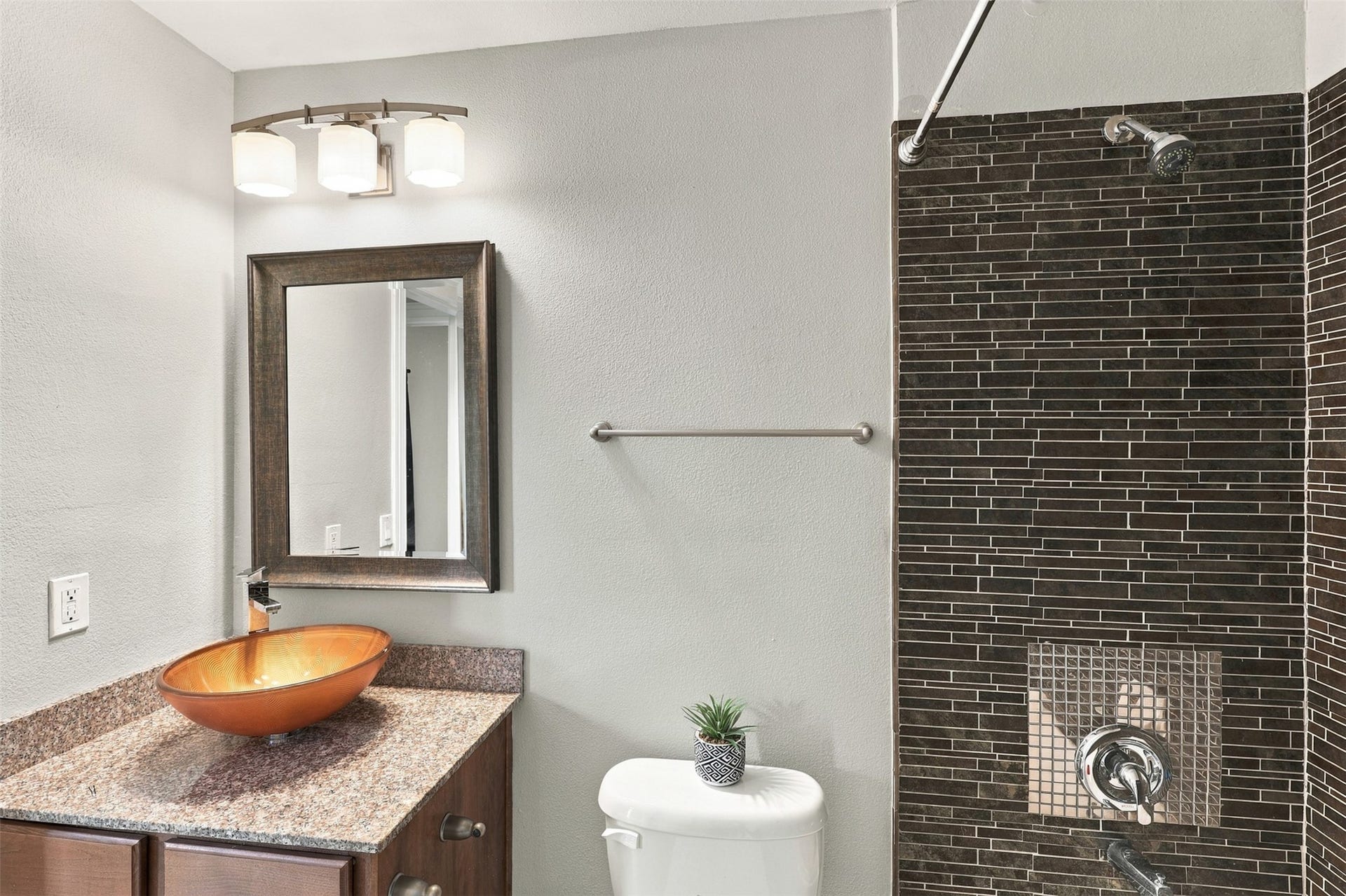 3501 Chenevert Street, #3, Houston, TX 77004 Modern bathroom featuring a stylish vessel sink, granite countertop, and sleek dark tile shower for a contemporary touch.