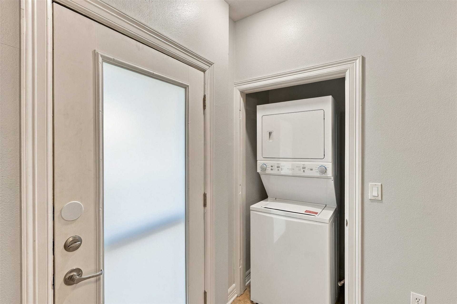 3501 Chenevert Street, #3, Houston, TX 77004 Convenient laundry nook with a stacked washer and dryer set, situated next to a frosted glass door for added privacy.