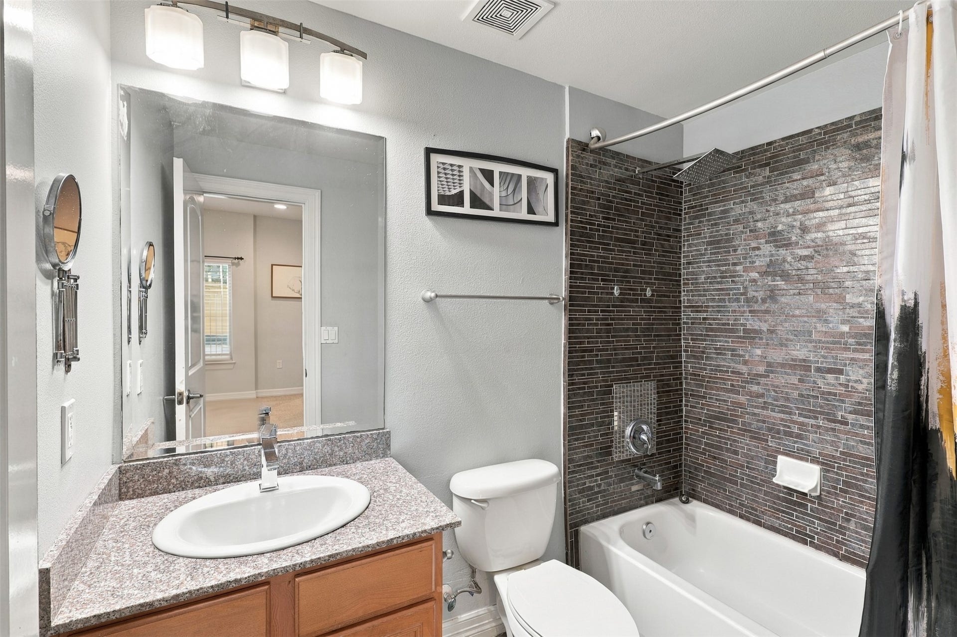 3501 Chenevert Street, #3, Houston, TX 77004 Modern bathroom featuring sleek dark tile, a granite countertop with a stylish sink, and ambient lighting.