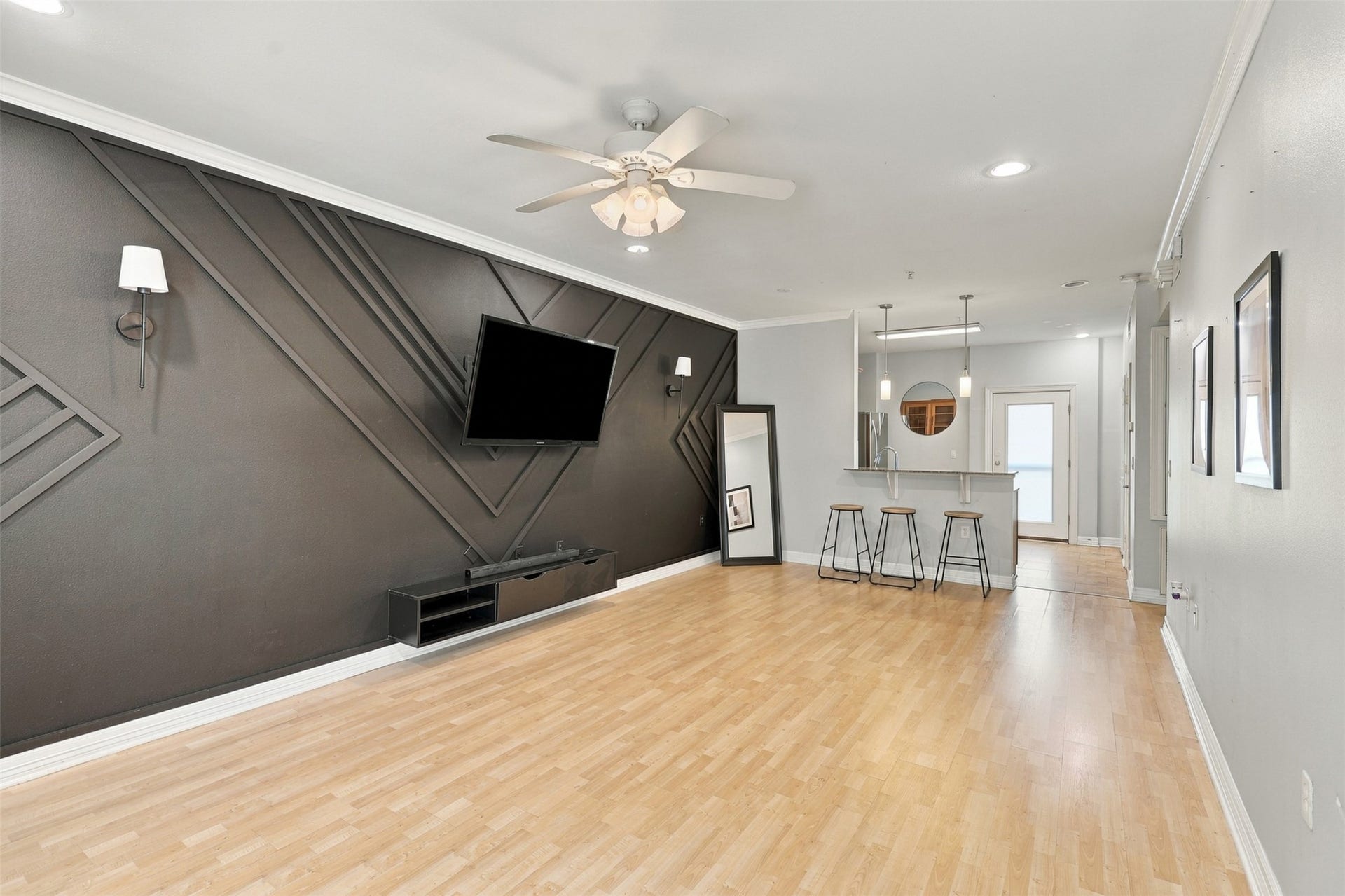 3501 Chenevert Street, #3, Houston, TX 77004 Chic living area with modern geometric accent wall, ceiling fan, and open layout leading to a cozy breakfast bar and kitchen.