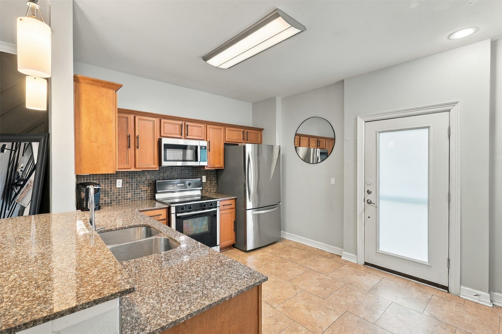 3501 Chenevert Street, #3, Houston, TX 77004 Modern kitchen with stainless steel appliances, granite countertops, and warm wood cabinetry, offering a sleek and inviting cooking space.